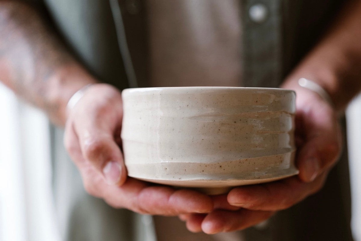 Close-up of hands gently holding a handmade ceramic matcha bowl (chawan) with a natural matte glaze — crafted by IKKAI Ceramics.