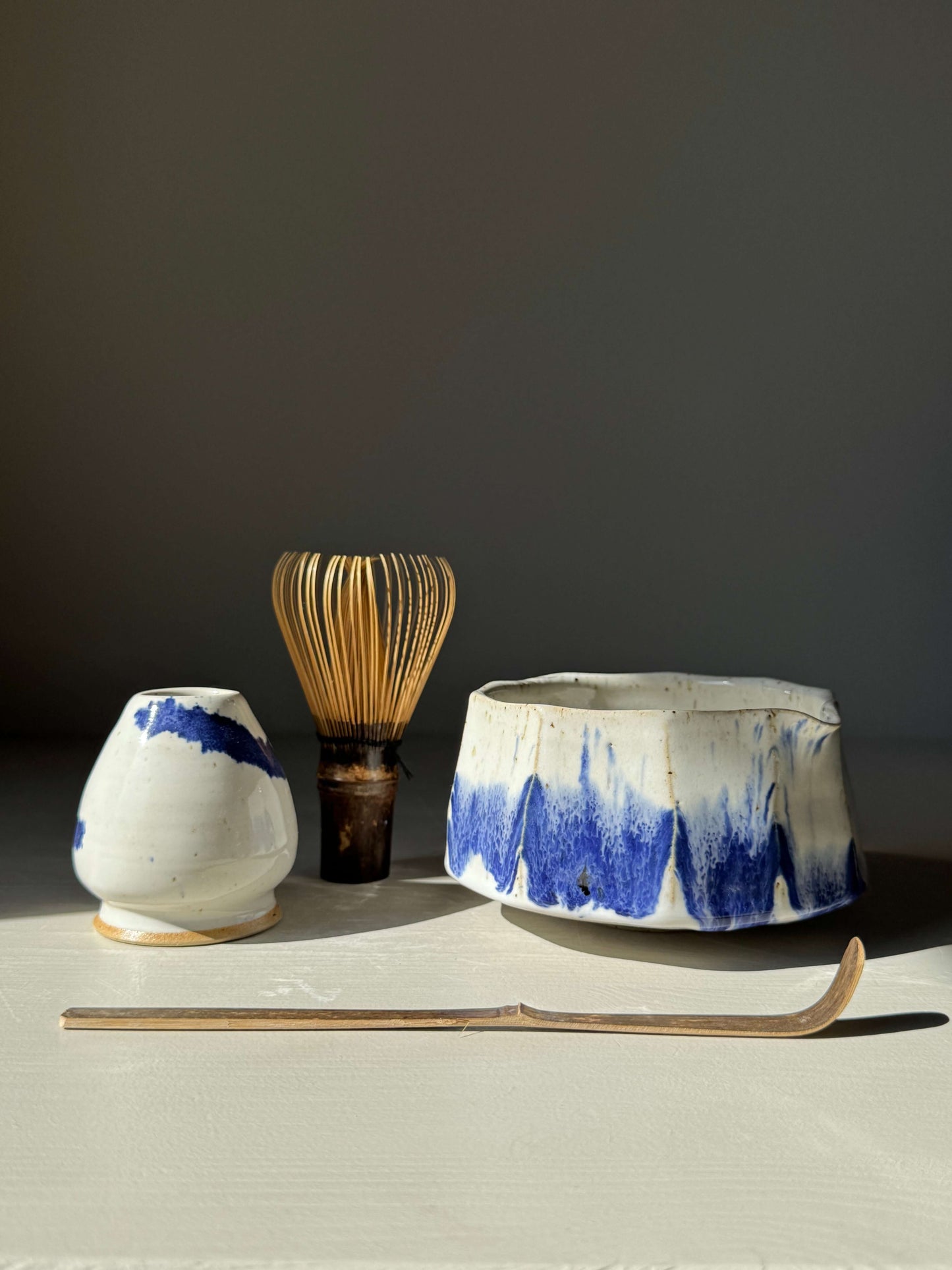 Faceted Matcha Bowl with Spout – Cobalt Blue & Glossy White Glaze #01, handmade ceramic with bamboo whisk and white ceramic holder.