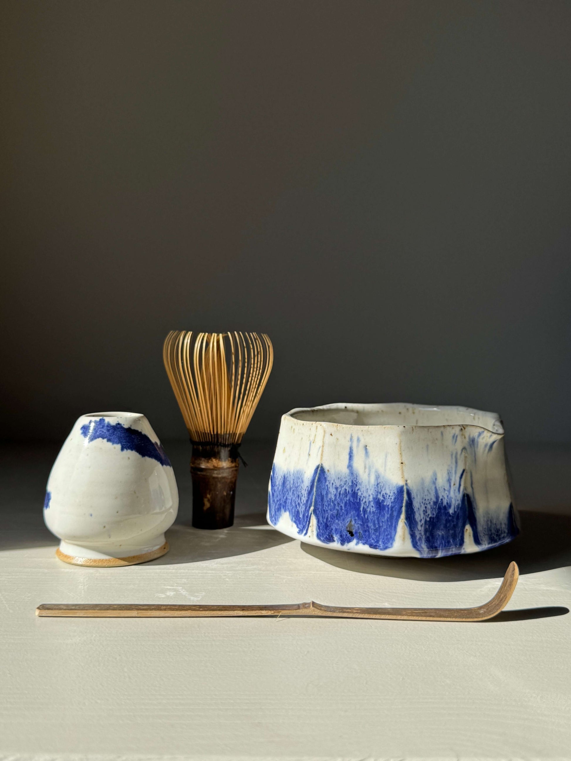 Faceted Matcha Bowl with Spout – Cobalt Blue & Glossy White Glaze #01, handmade ceramic with bamboo whisk and white ceramic holder.