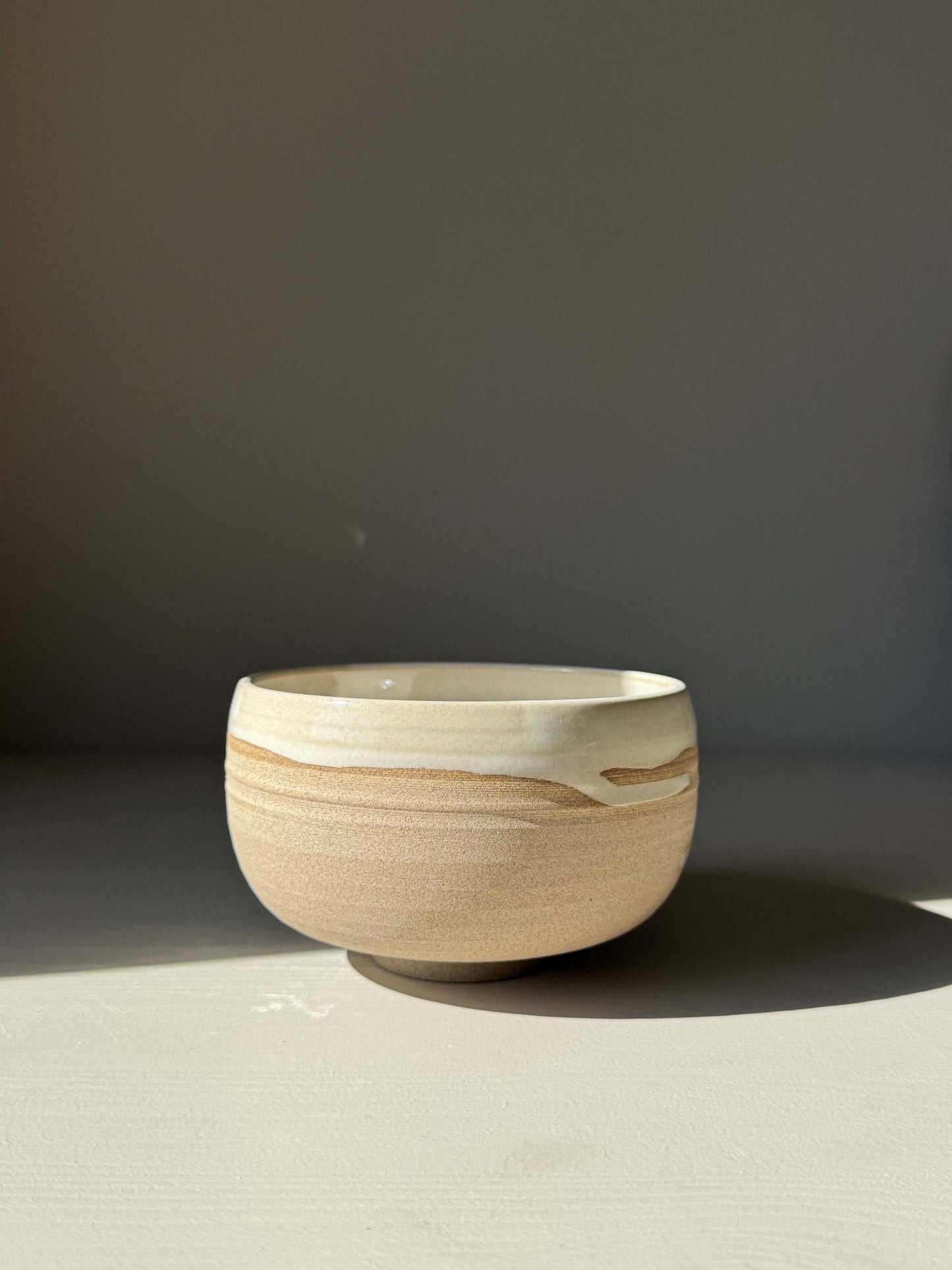 Handmade ceramic Matcha Bowl – Yuki Series #03 with toffee clay and white glaze finish on display.