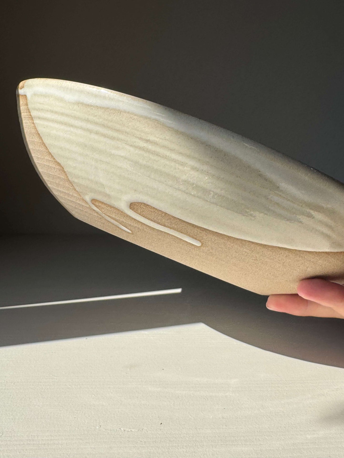 Hand holding Large Shallow Bowl - Yuki Series, handmade ceramic with white glaze and raw clay detailing, perfect for salads or shared meals.