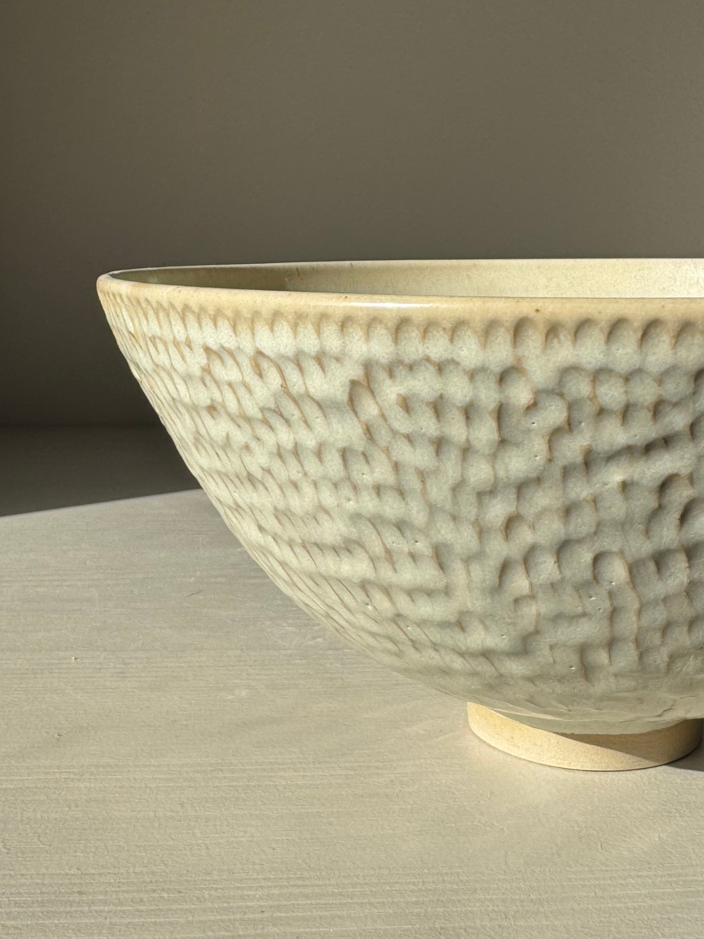 Medium Bowl – Moonstone with creamy satin finish, hand-carved texture, and warm rim detail catching light, elegant tableware.