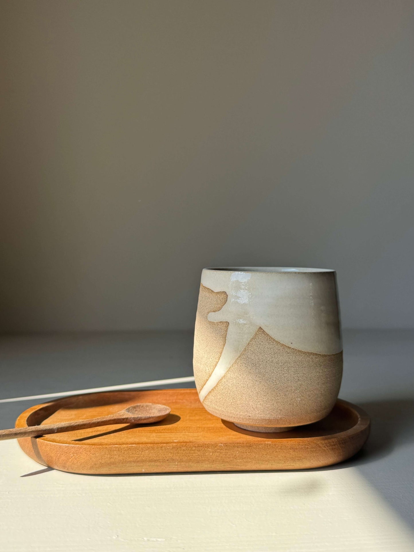 Yunomi Cups - Yuki Series handmade ceramic cup with white glaze on toffee clay on wooden tray.