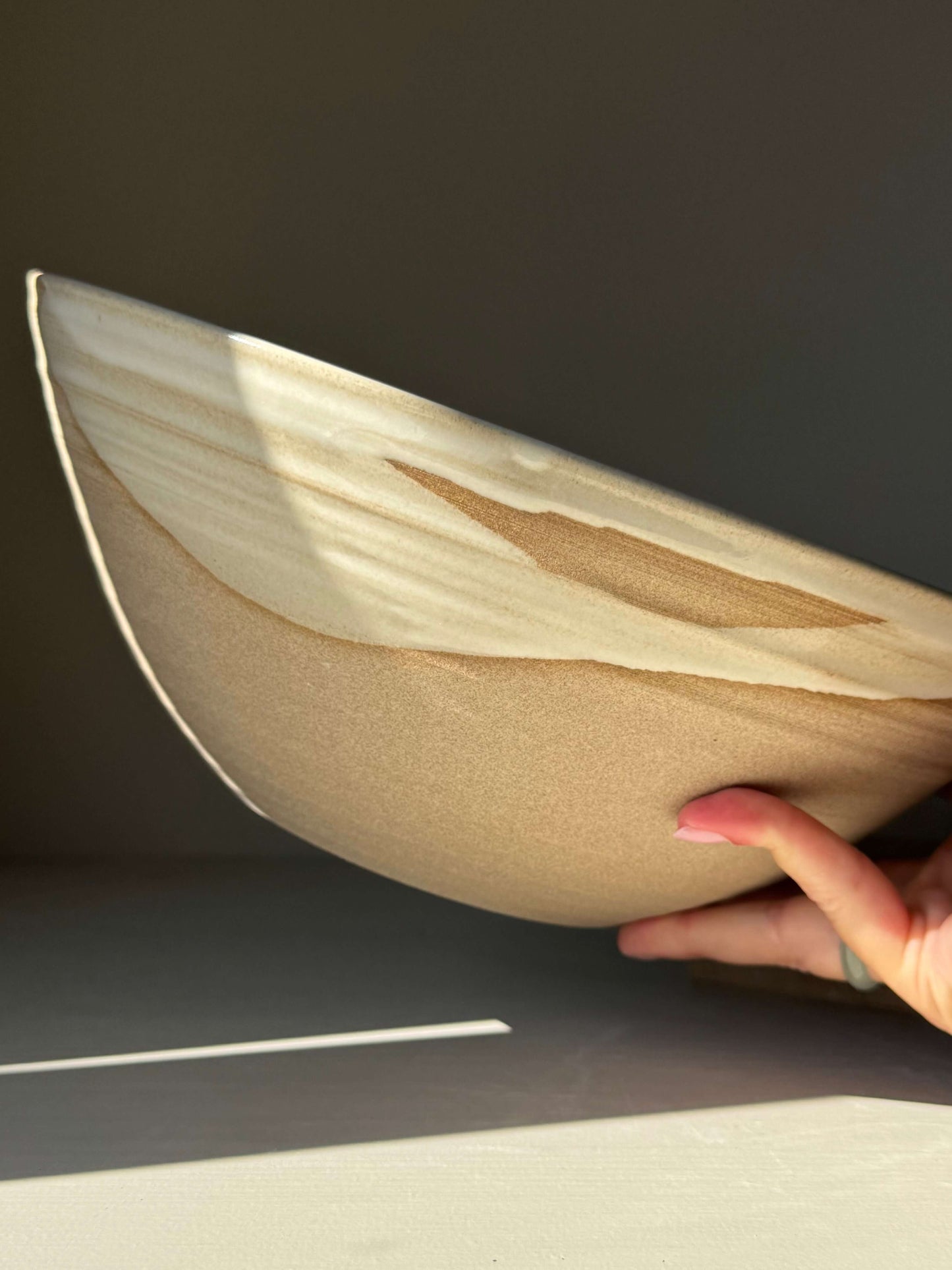 Handmade ceramic Large Bowl - Yuki Series with white glaze over raw clay, highlighting its deep, rounded form in natural light.