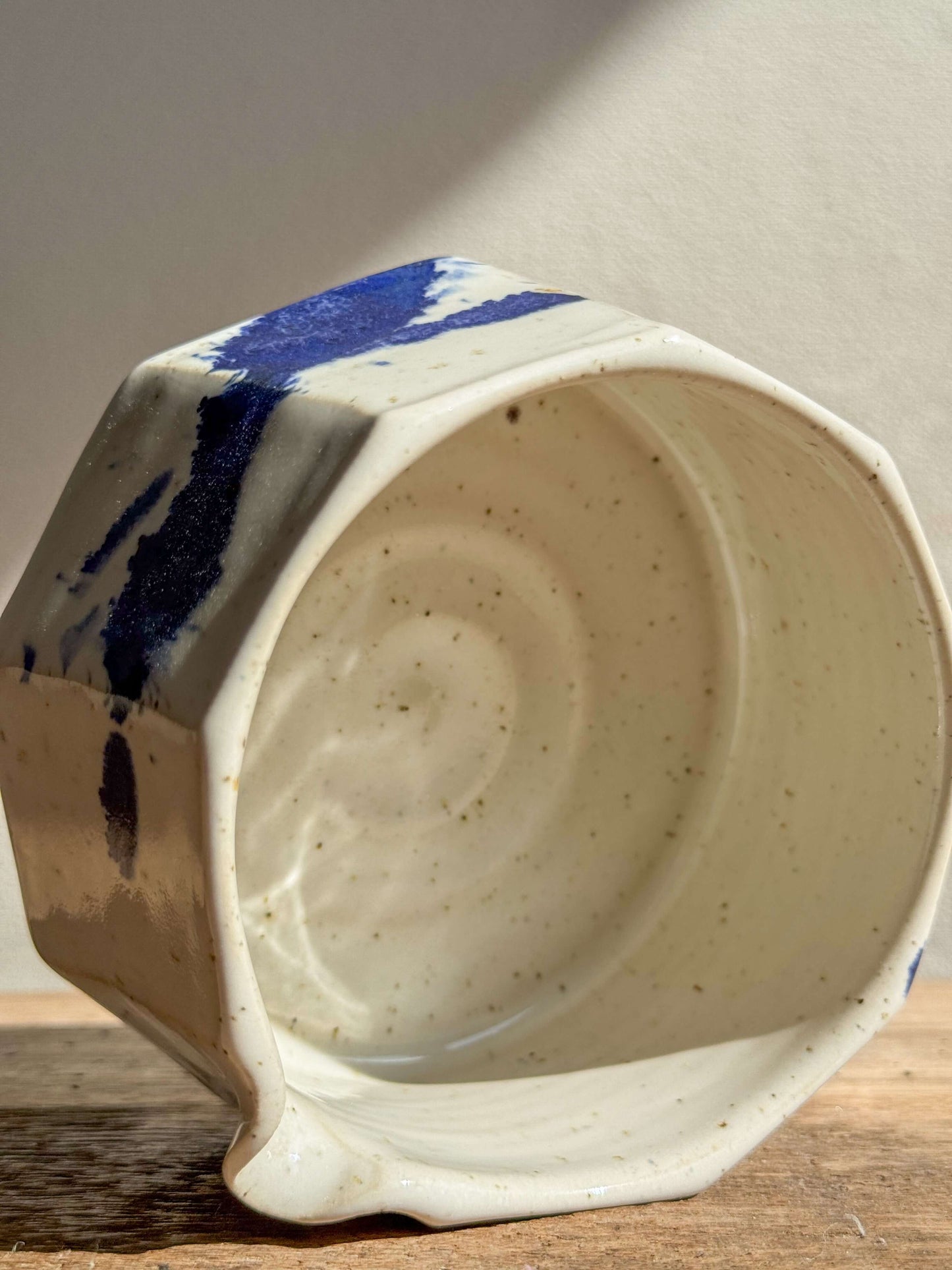 Faceted matcha bowl with spout in glossy white glaze and cobalt blue accents, showing unique shape and design. Ideal for modern decor.
