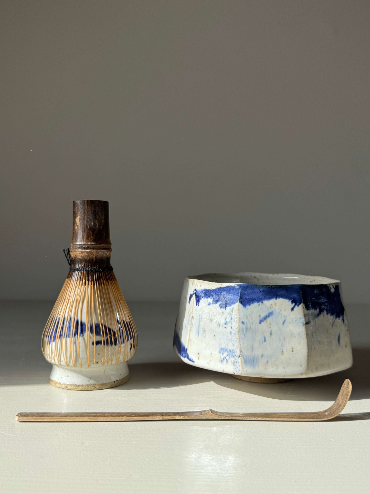 Handmade ceramic Faceted Matcha Bowl – Cobalt Blue & Glossy White Glaze #05 with bamboo whisk and chashaku on a light background.