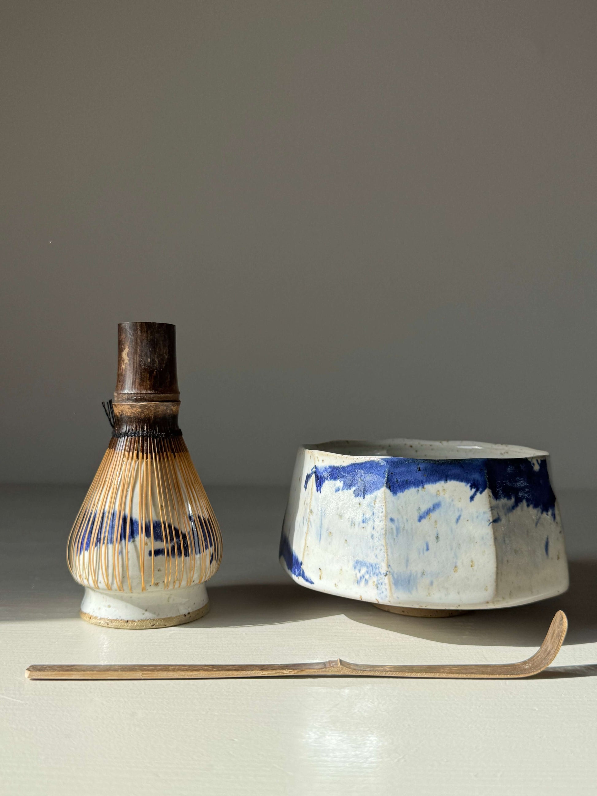 Handmade ceramic Faceted Matcha Bowl – Cobalt Blue & Glossy White Glaze #05 with bamboo whisk and chashaku on a light background.