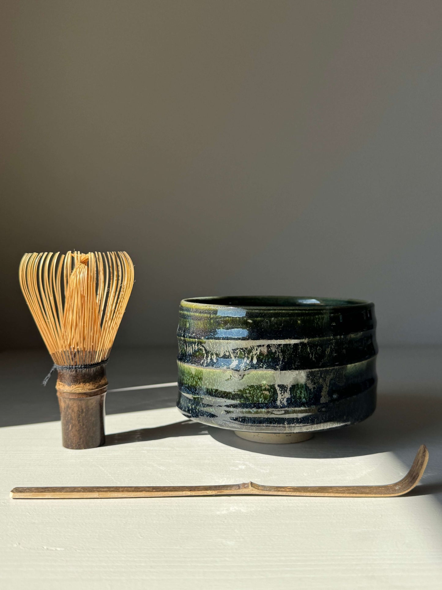Textured Matcha Bowl - Hinoki Series #04 with green glaze, handmade ceramic design next to a bamboo whisk and chashaku.