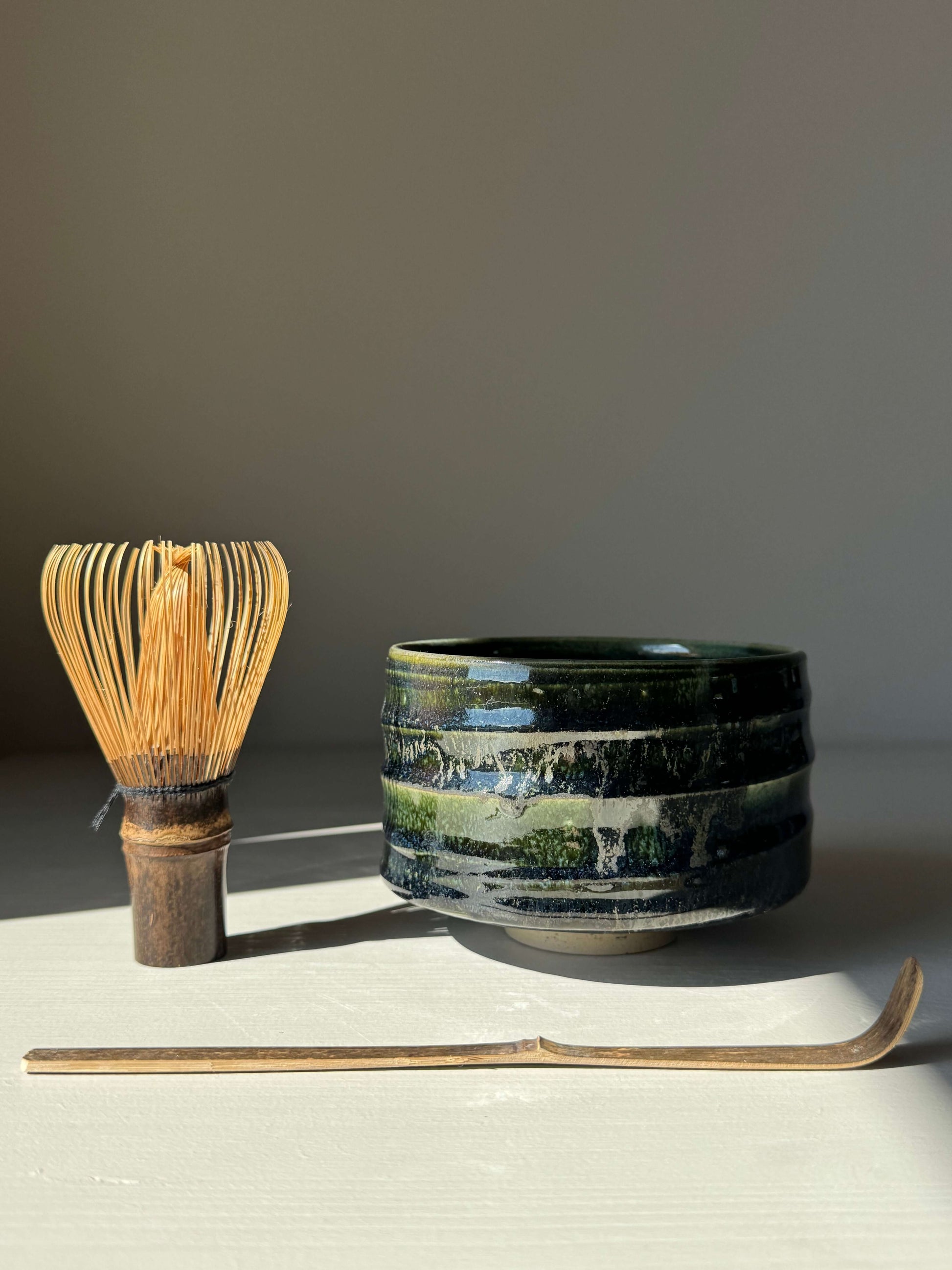 Textured Matcha Bowl - Hinoki Series #04 with green glaze, handmade ceramic design next to a bamboo whisk and chashaku.