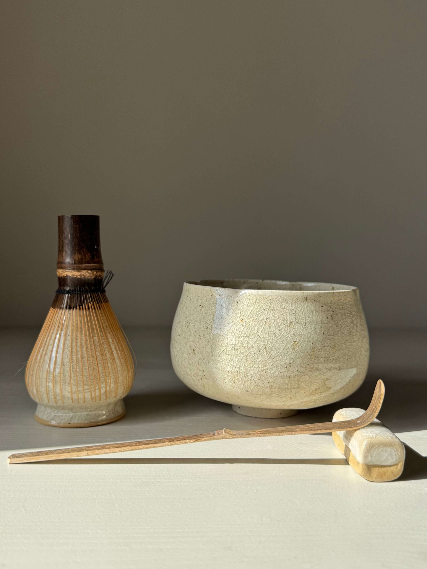 Matcha Bowl - Kannyū #01, handmade ceramic bowl with crackle glaze, alongside bamboo whisk and scoop on a neutral background.