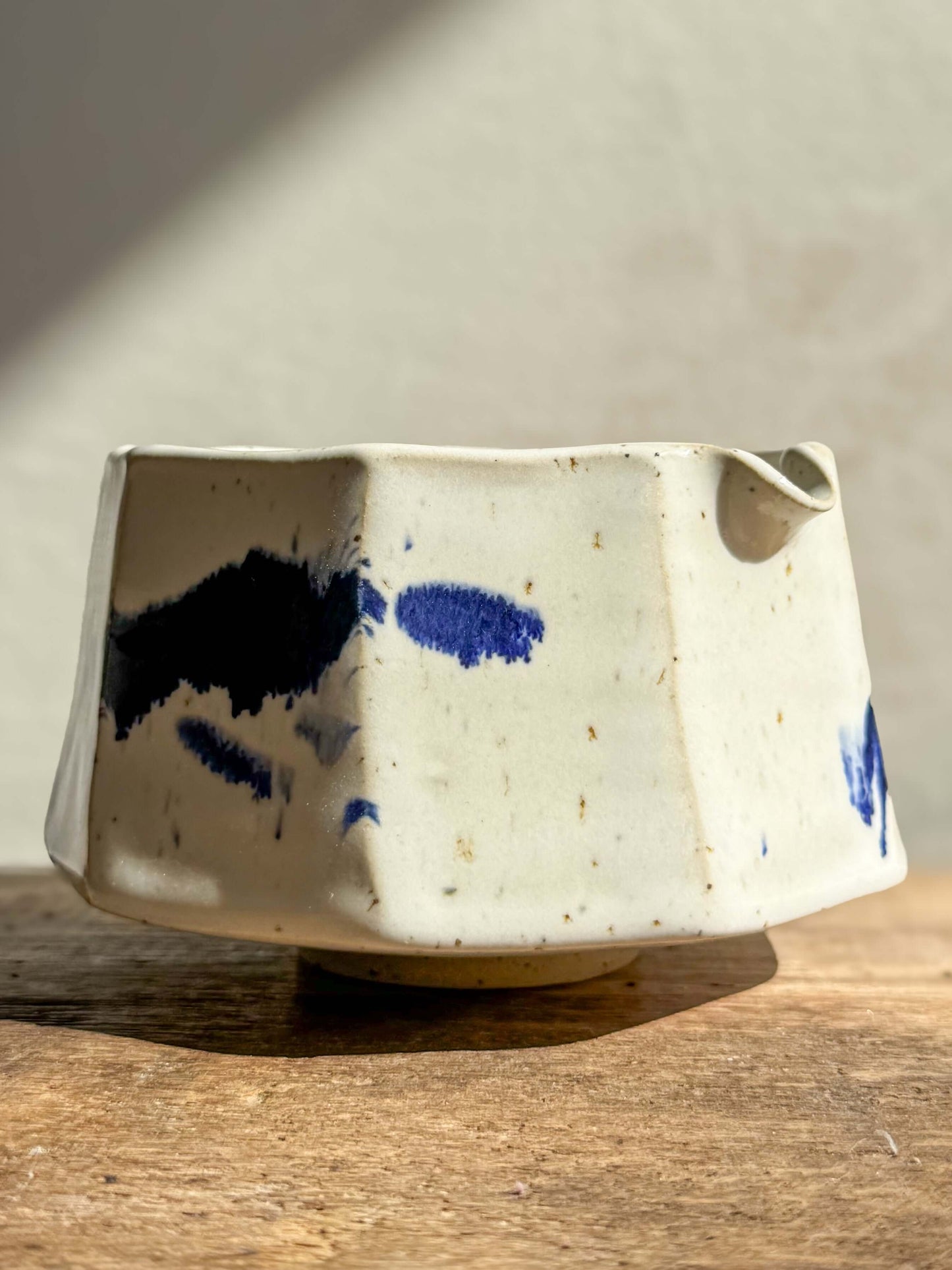 Faceted matcha bowl with spout in cobalt blue and glossy white glaze, featuring a modern design and textured facets.