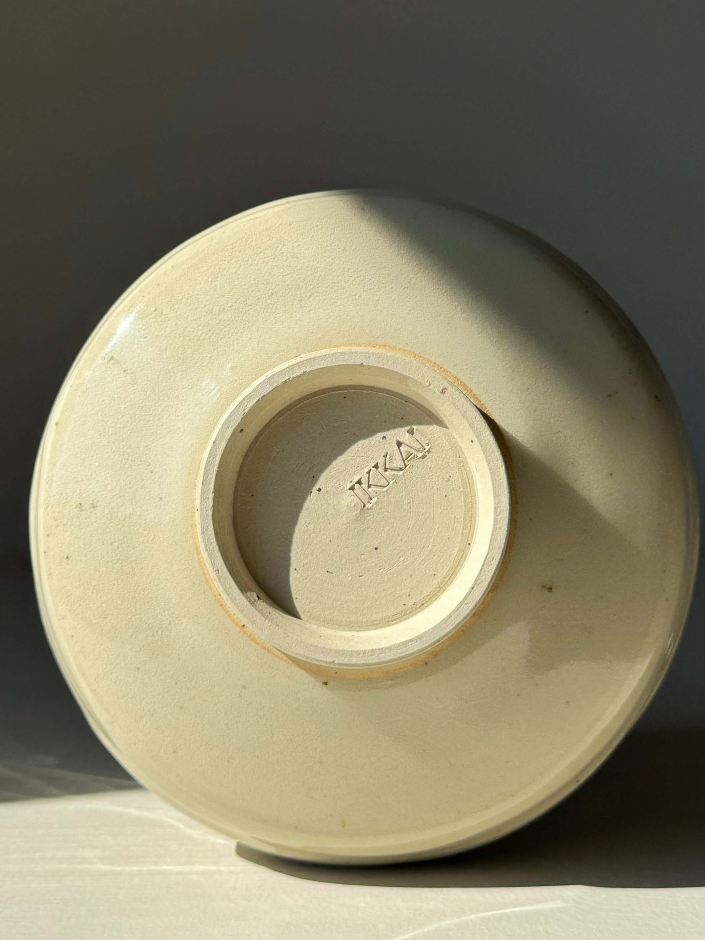 Underside view of a textured matcha bowl with clear glaze, showing natural stoneware finish and maker's mark at the base.