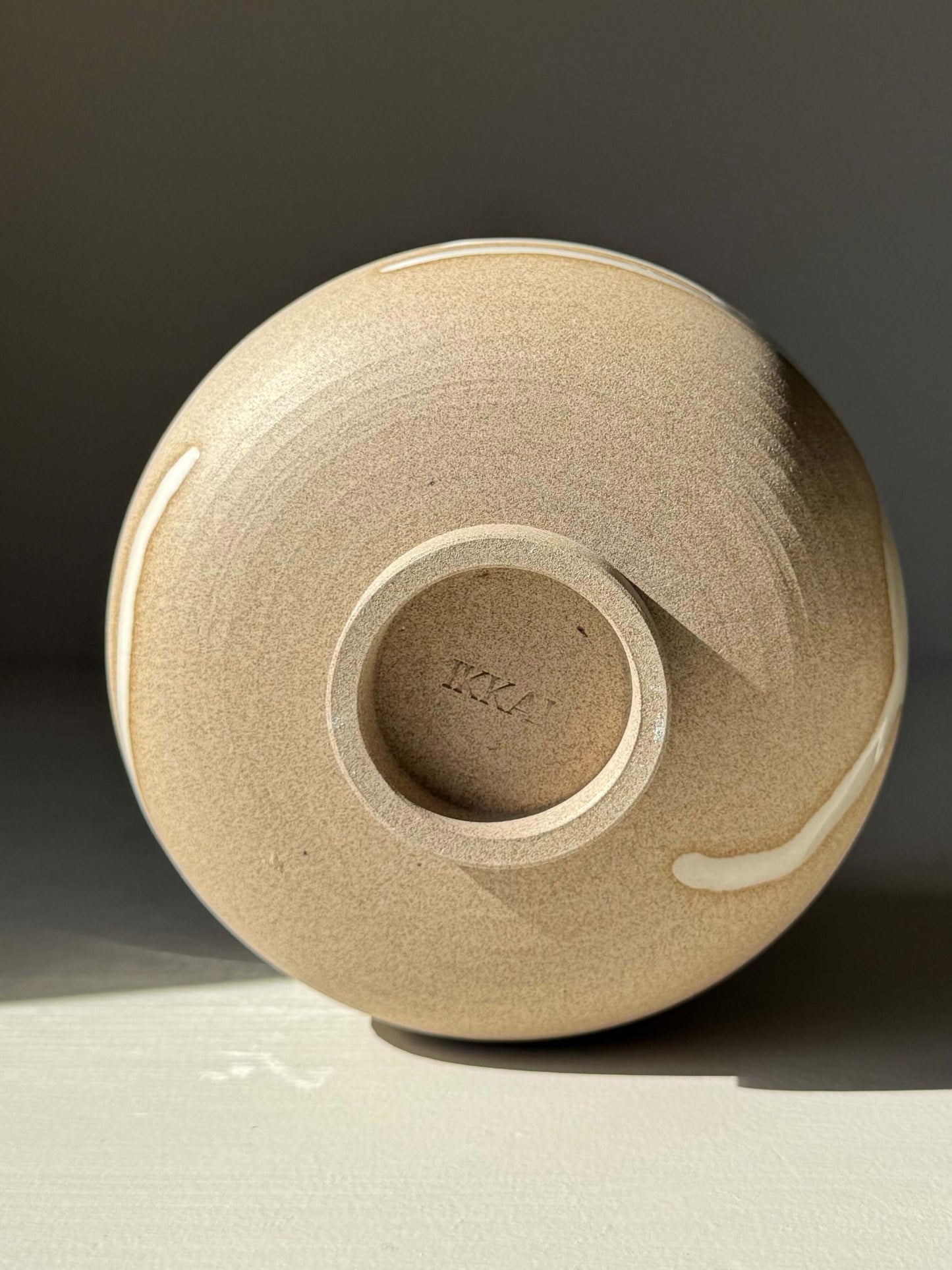 Bottom view of a Matcha Bowl – Yuki Series #01, a handmade ceramic piece with toffee clay and white glaze, showcasing natural glaze drips.