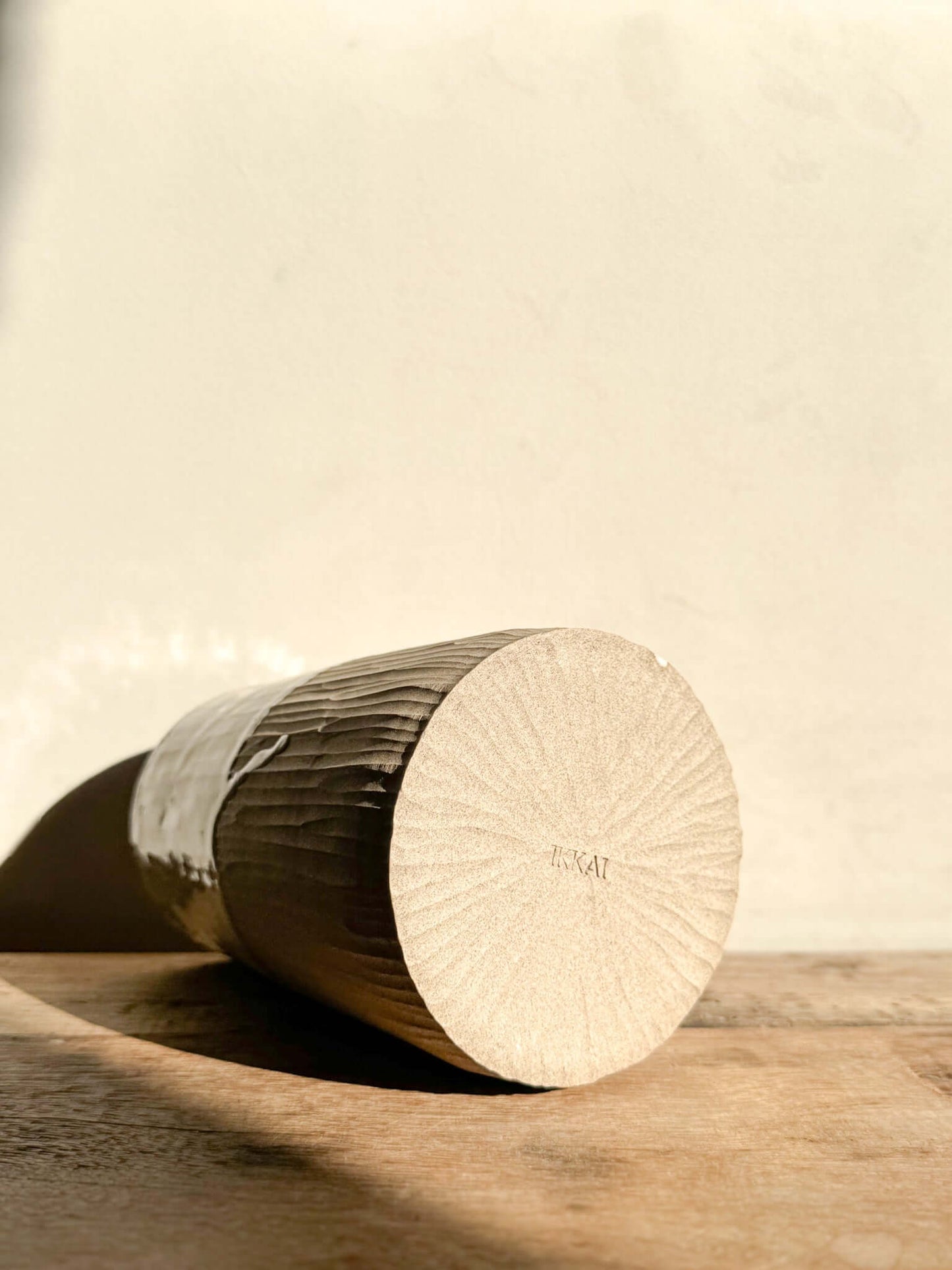 Medium Vase/Jug from Yuki Series with hand-carved vertical lines, glossy white glaze, and unglazed base, lying on wooden surface.