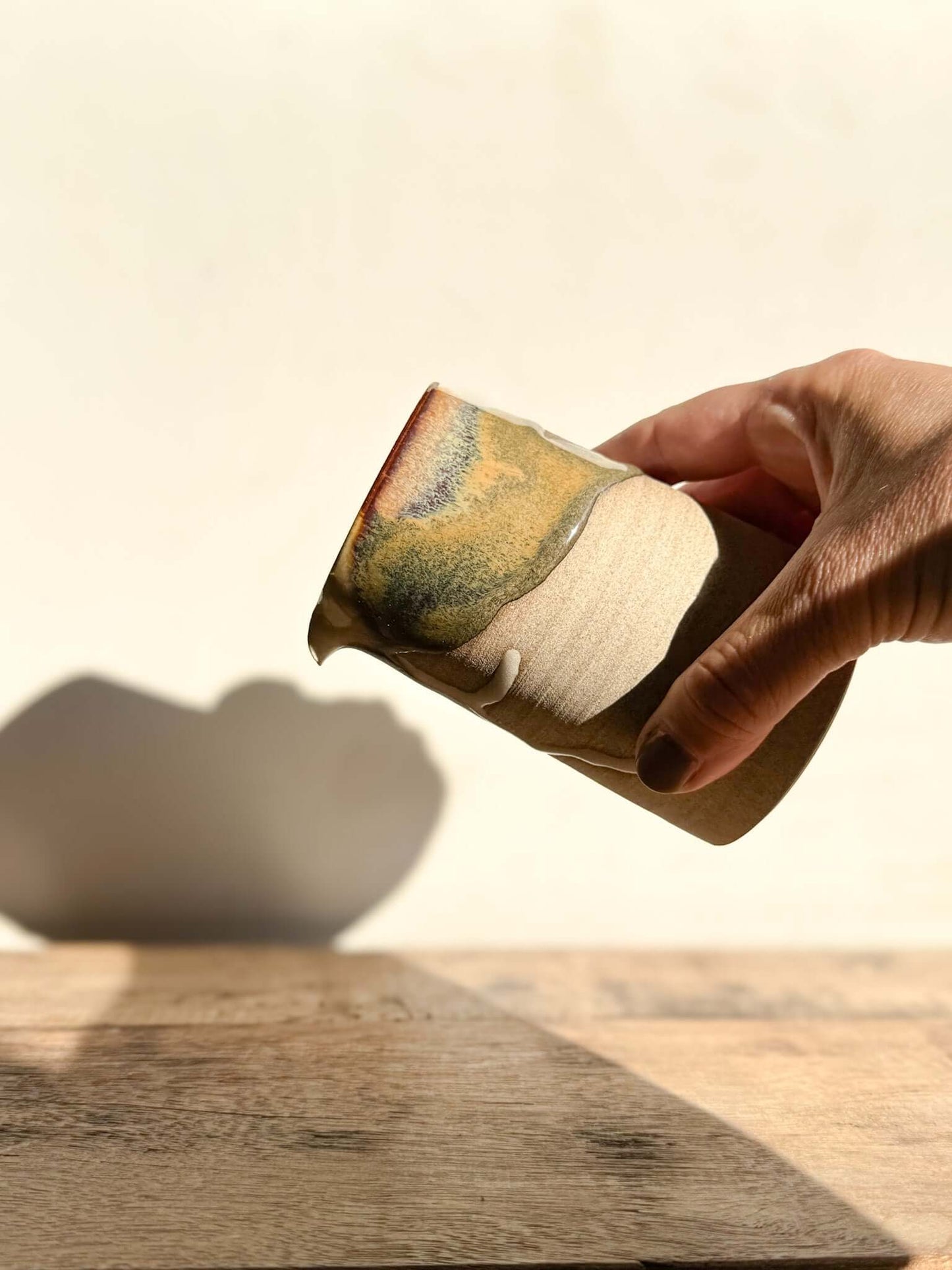 Hand holding Small Vase from Inyo Series 02, showcasing natural glaze drips on sculptural form, blending raw texture and smooth clay.