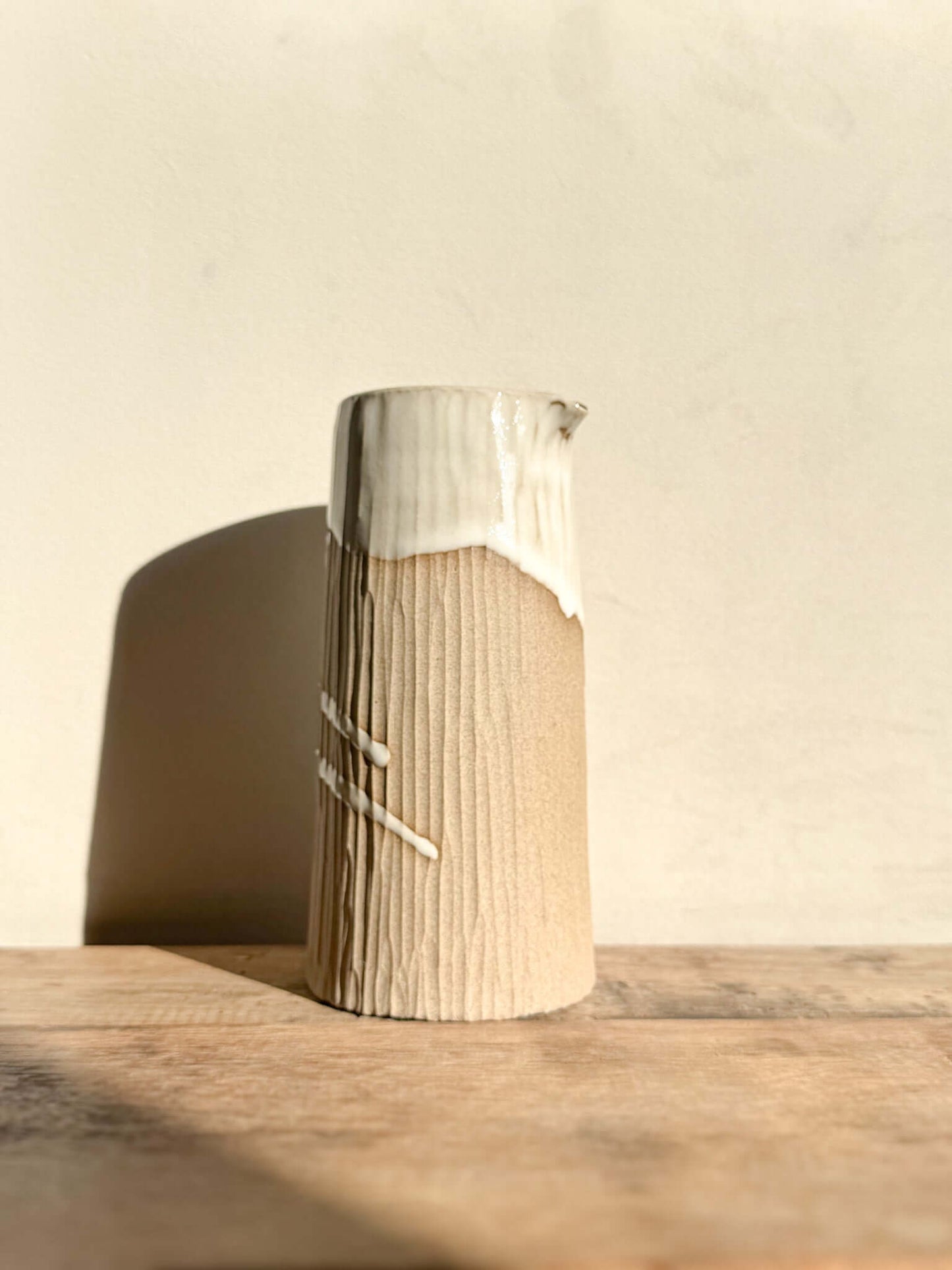 Medium vase from Yuki Series, features hand-carved lines, glossy white glaze top, raw base, sculptural piece for flowers or serving.