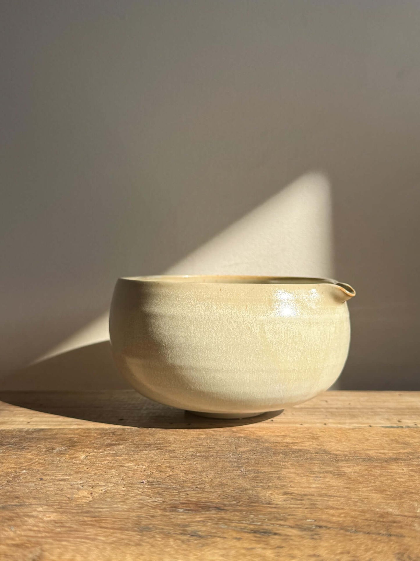 Katakuchi Matcha Bowl with Spout in Moonstone glaze on wooden surface, highlighting its soft, rounded design and smooth pouring spout.