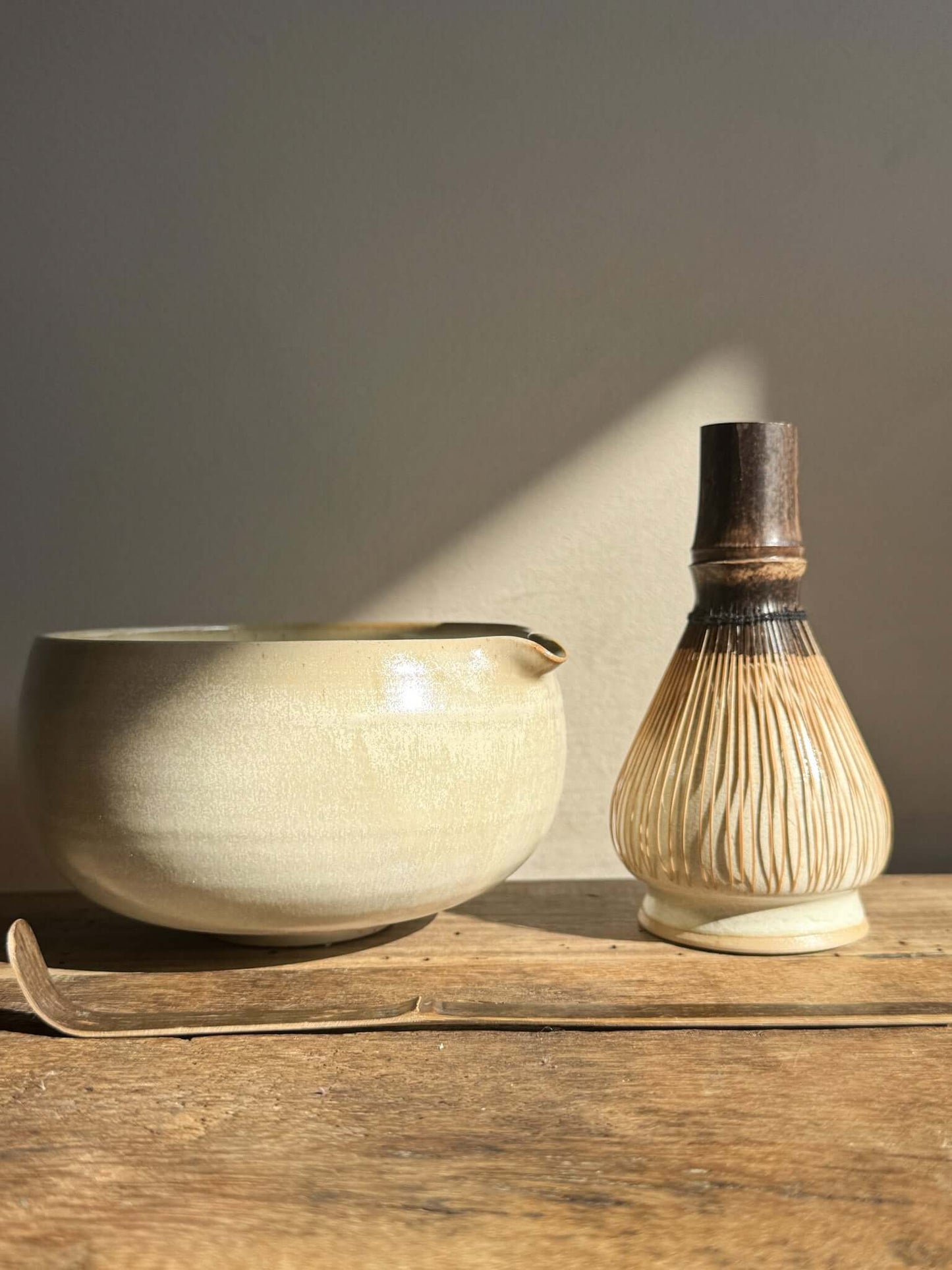 Moonstone glazed Katakuchi matcha bowl with spout, whisk, and ladle on wooden surface in natural lighting.