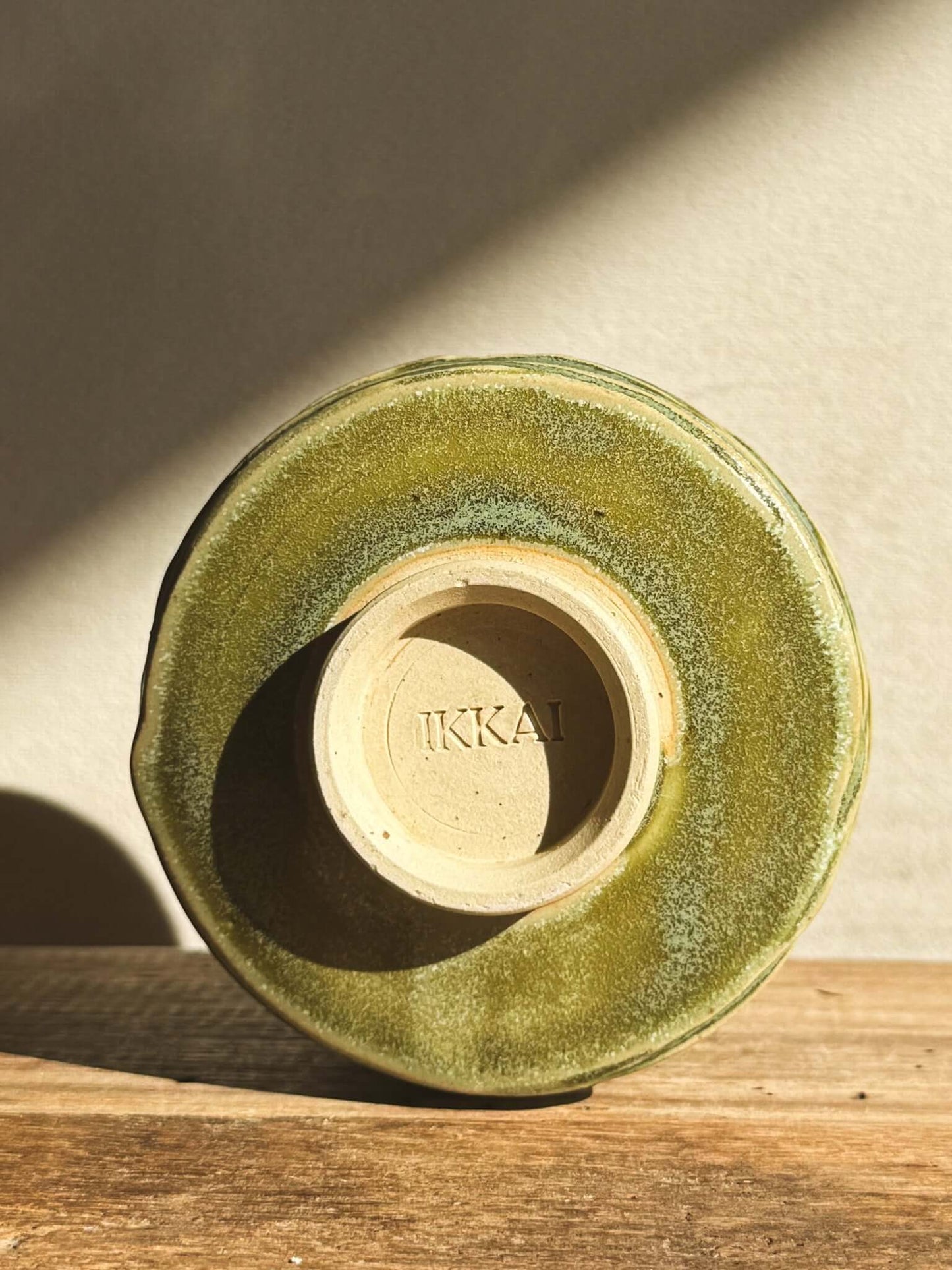 Base view of Wasabi Green Yunomi cup with carved texture and signature, showing unique glaze and craftsmanship detail.