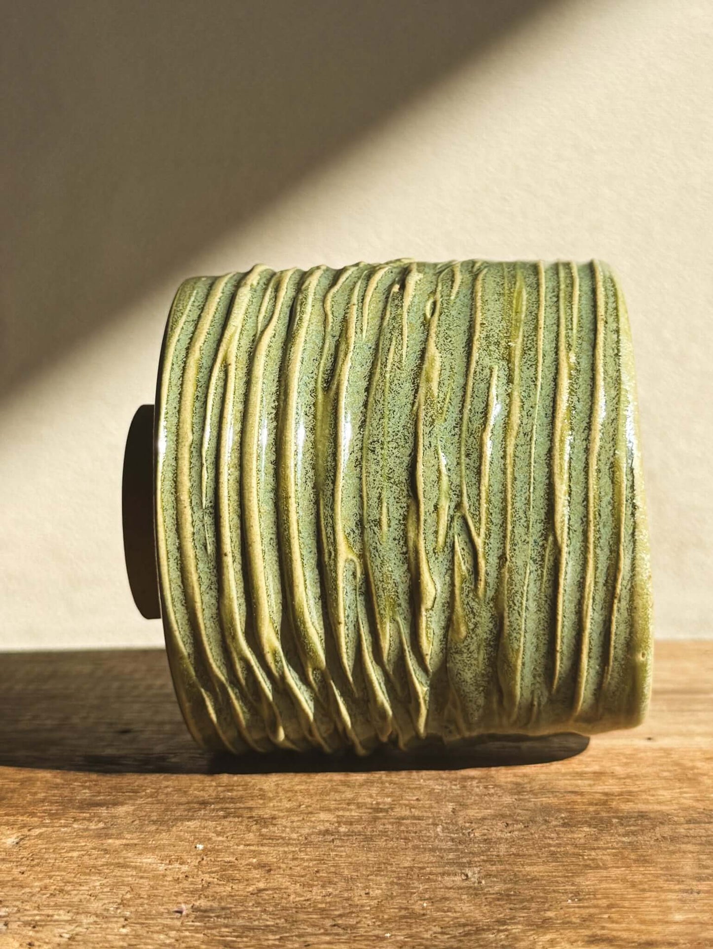 Wasabi Green Yunomi Cup #02 with textured glaze, carved in flowing waves, on wooden surface. Tall, flared lip design. Size: 8x7.5 cm