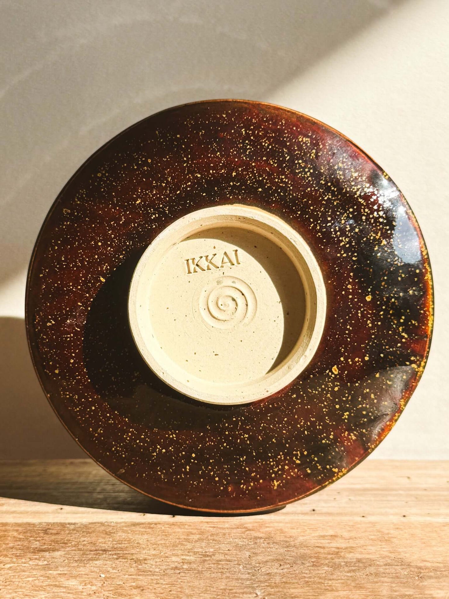 Kinsei Matcha Bowl with warm amber tones and layered glaze reflecting light, rich in earthy colors, bottom view