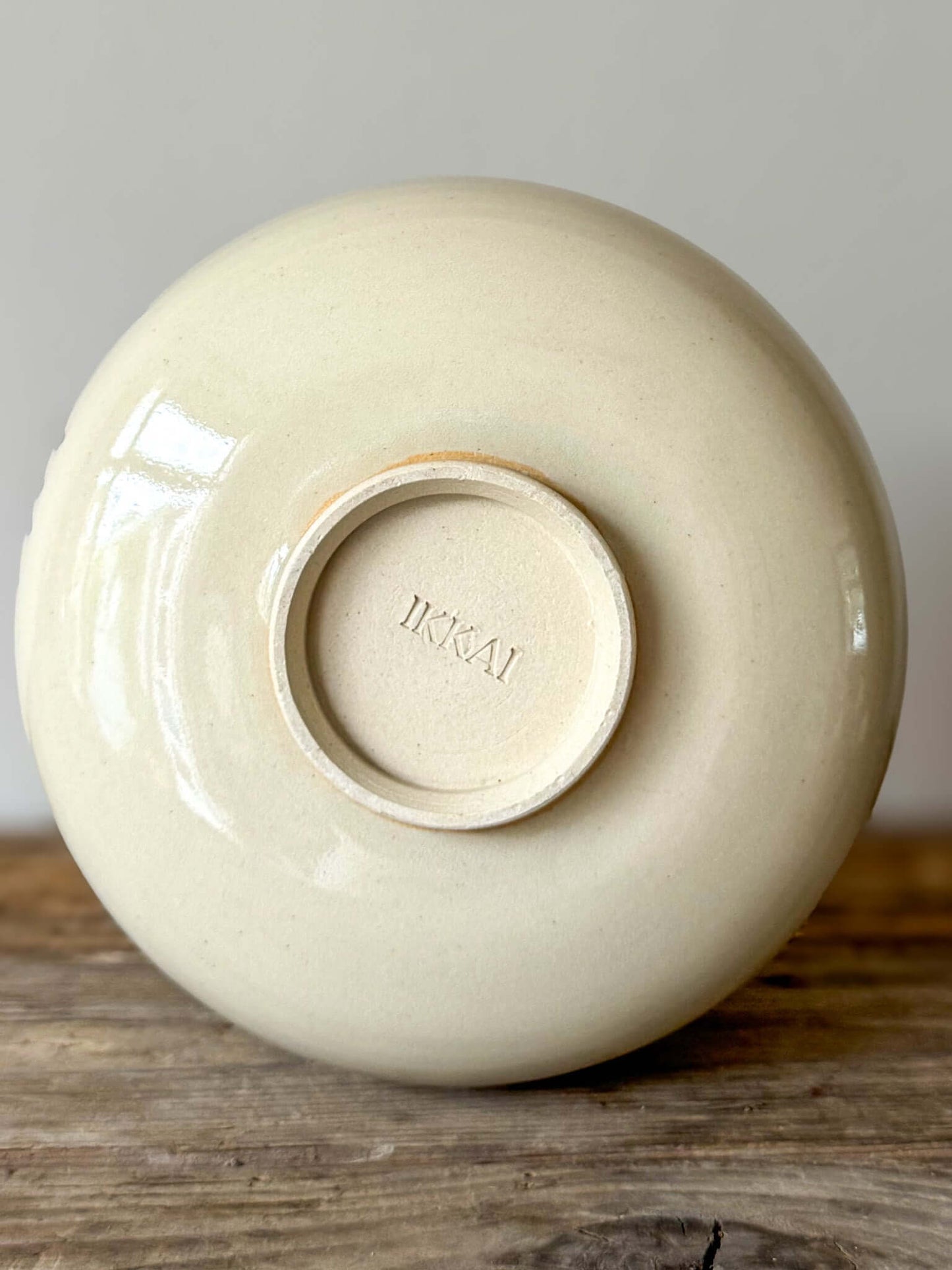 Underside of Large Rounded Matcha Bowl from Gosu Series showing artist's mark, placed on a wooden surface. Elegant ceramic design.