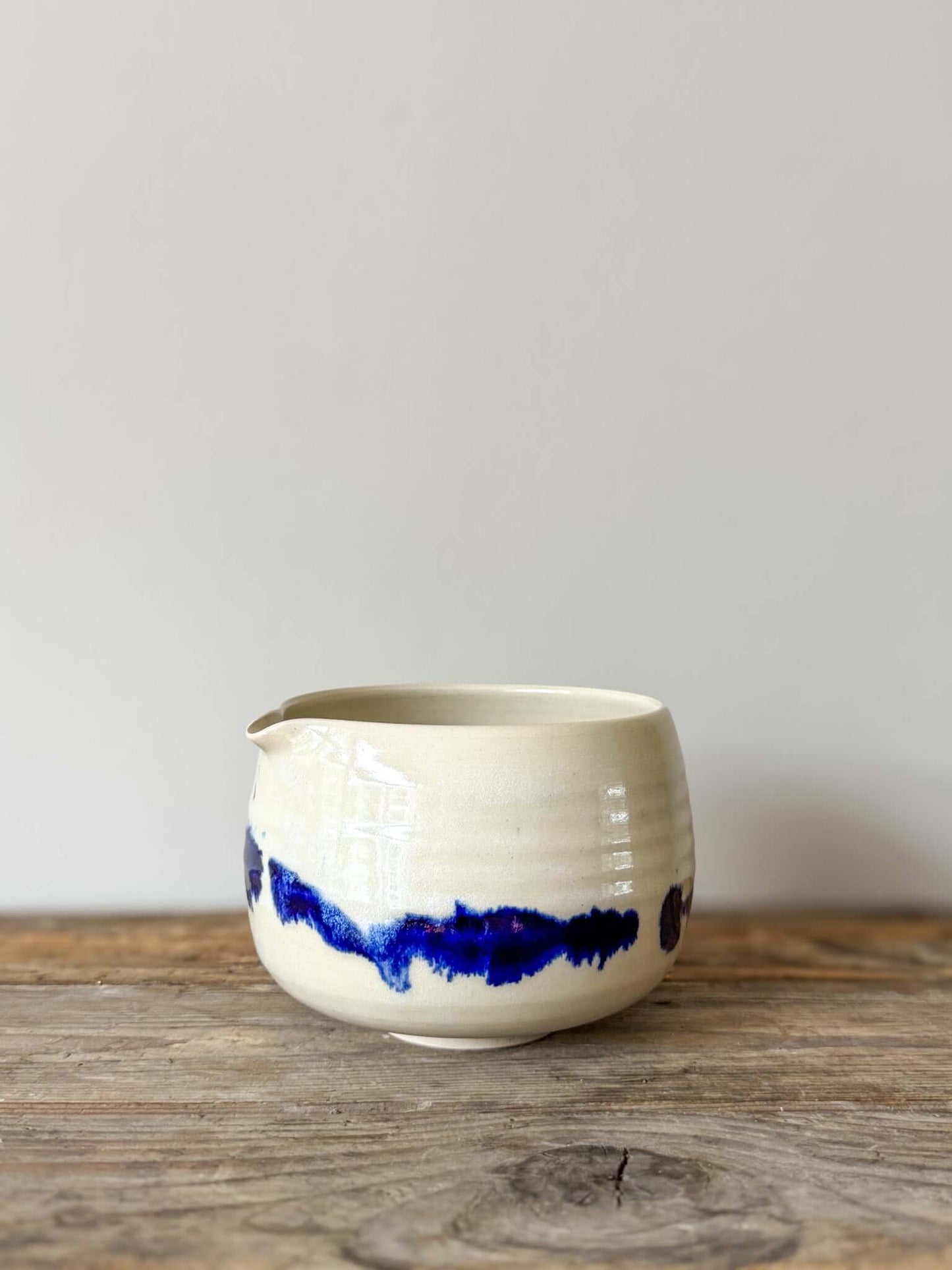 Katakuchi Matcha Bowl with cobalt blue glaze, featuring a spout from the Gosu Series. Unique splattered patterns on a rustic wooden surface.