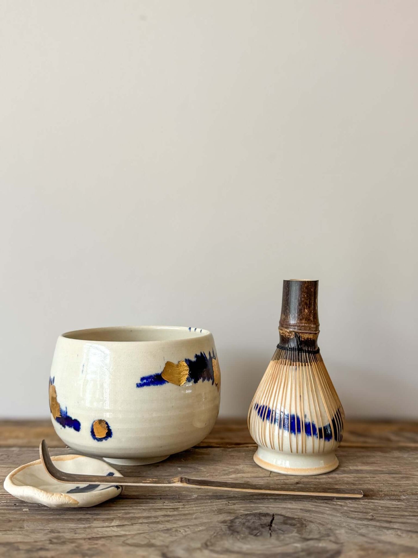 Rounded Matcha Bowl with cobalt glaze and gold leaf design, part of the Gosu Series, on a wooden surface with tea tools.