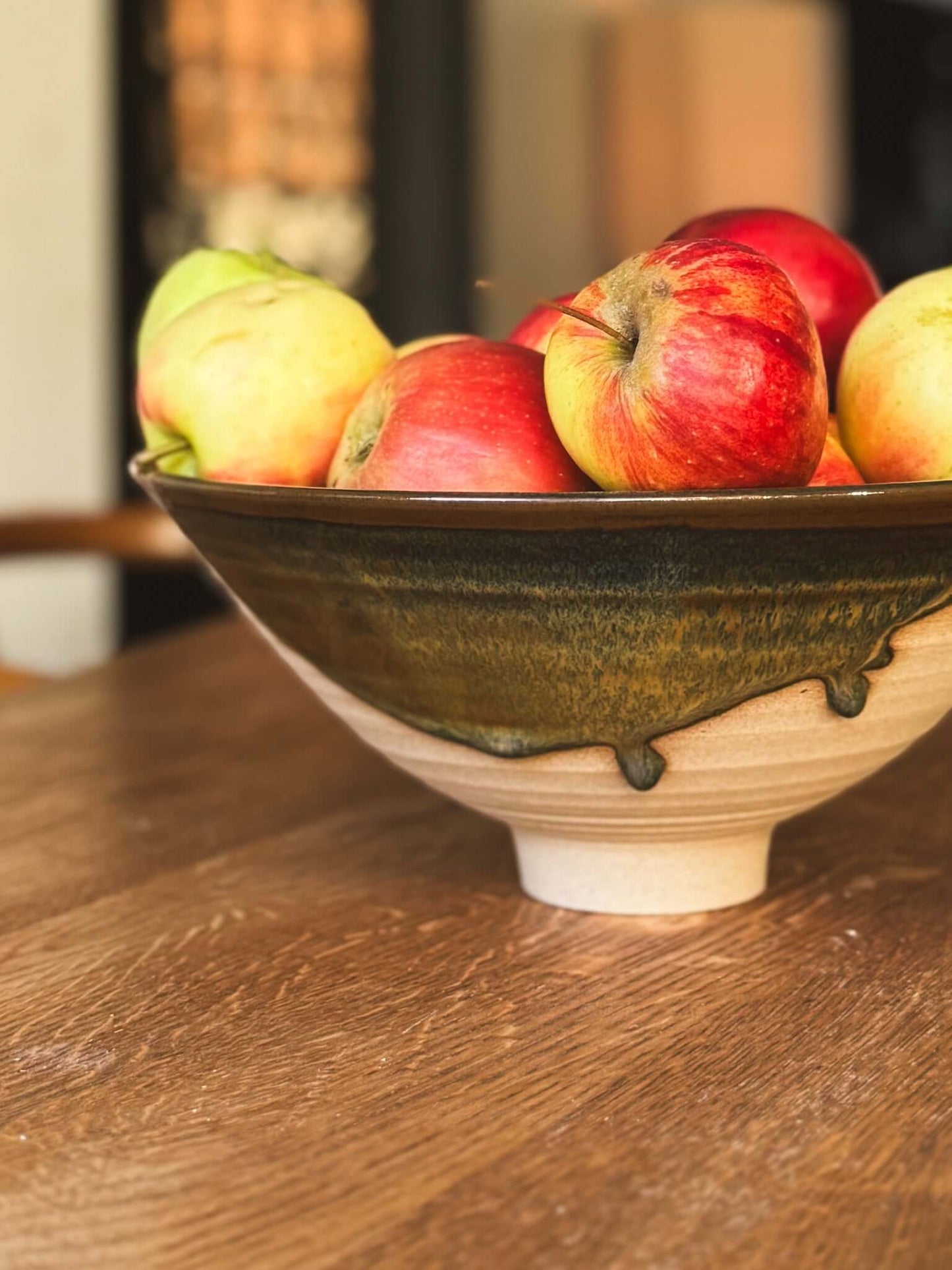 Medium Bowl - Inyo #01 with apples on wooden table, showcasing its sculptural design, golden tones, and carved exterior.