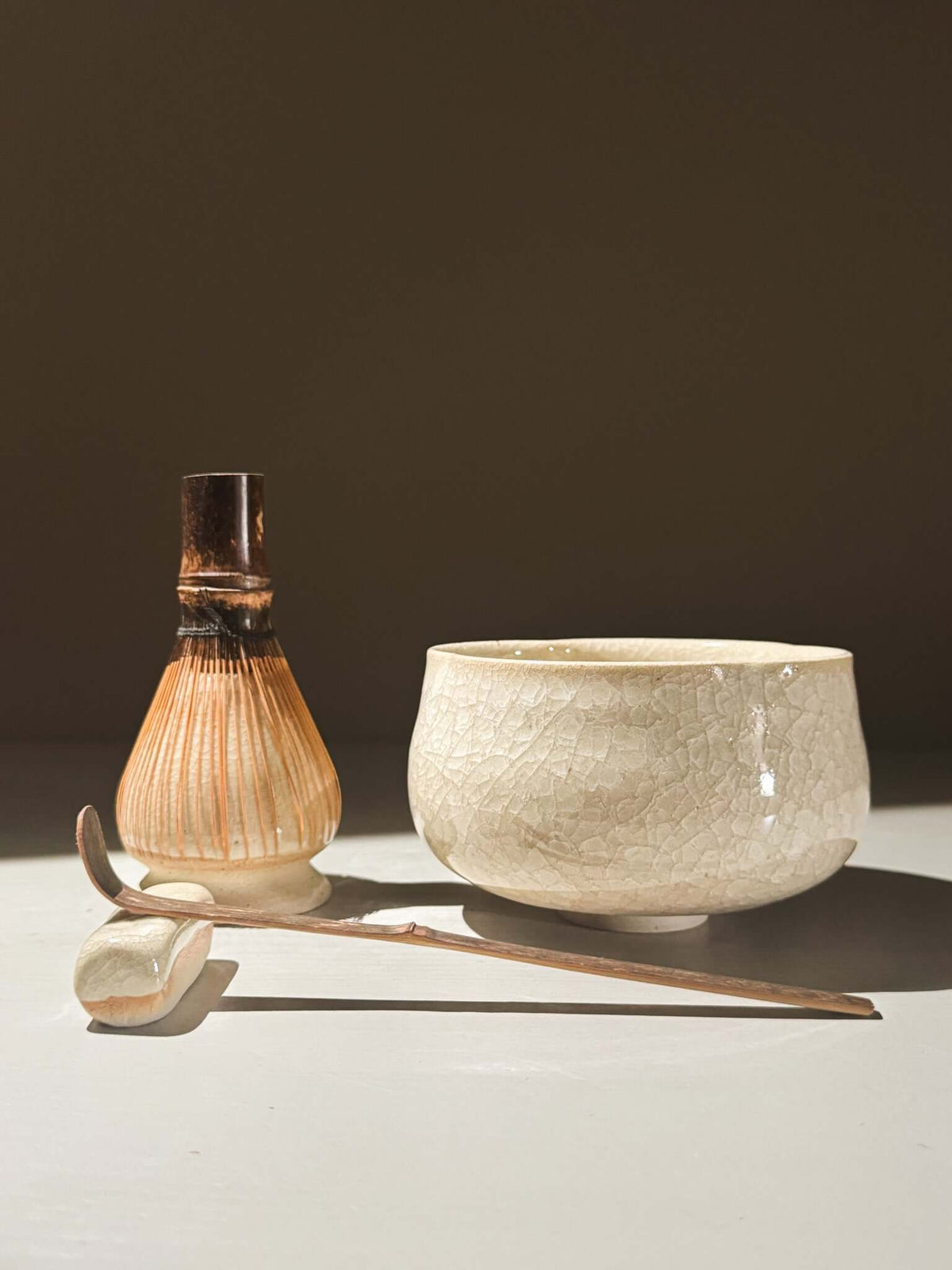 Matcha Bowl - Kannyū #07 with crackle glaze, bamboo whisk, and spoon on light background