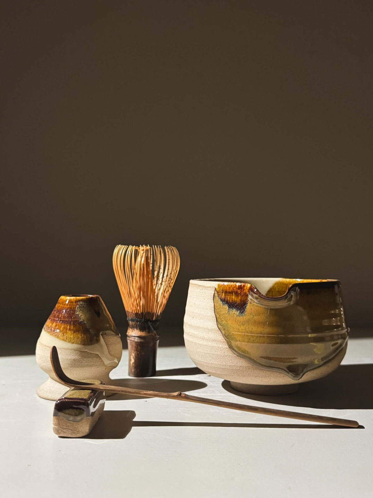 Matcha Bowl with Spout – Inyo #02 set, featuring handmade glazed stoneware with bamboo whisk and scoop, displayed in warm lighting.