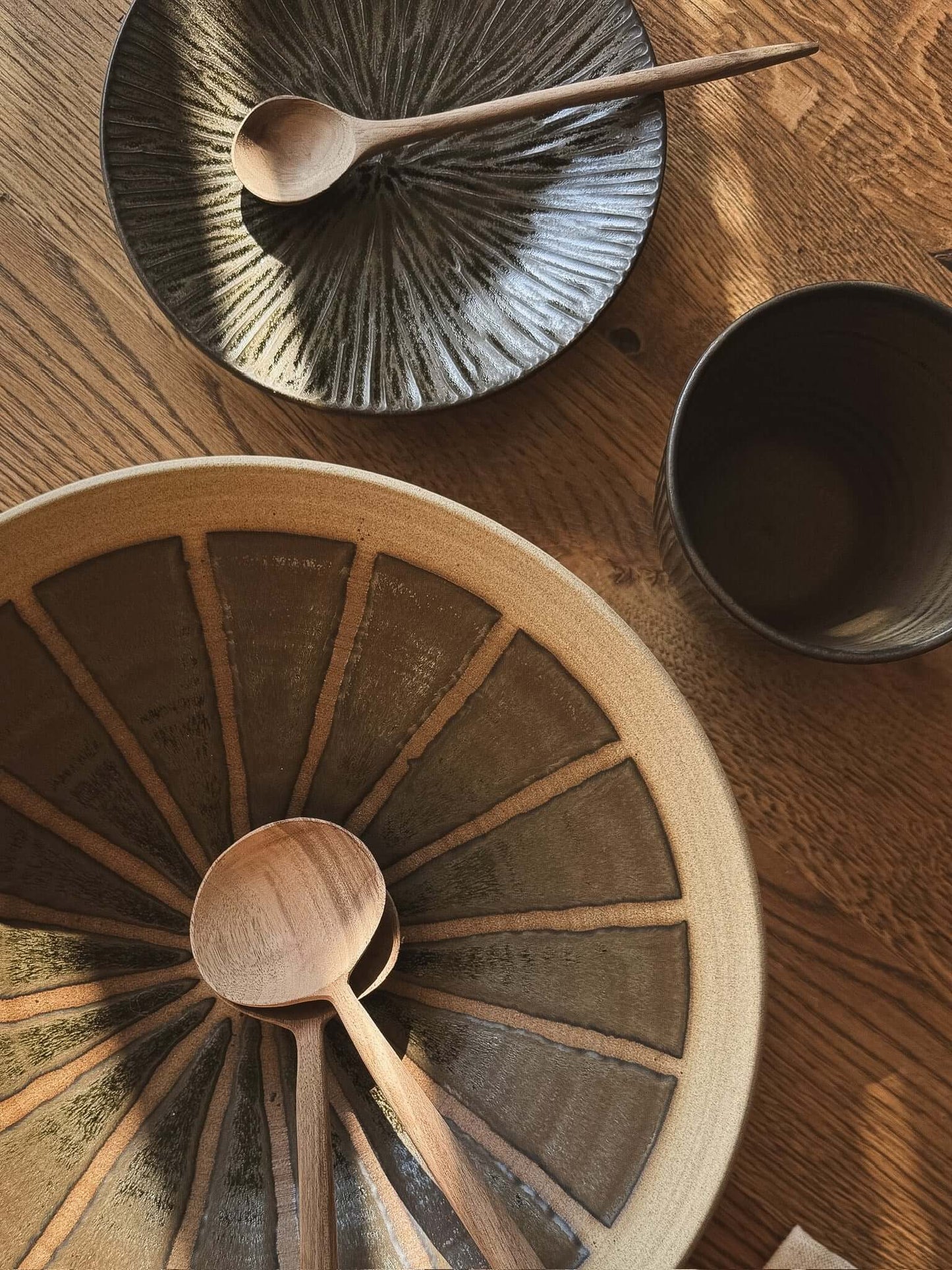 Medium Bowl - Black Truffle with radiating glaze pattern on wooden table with spoons