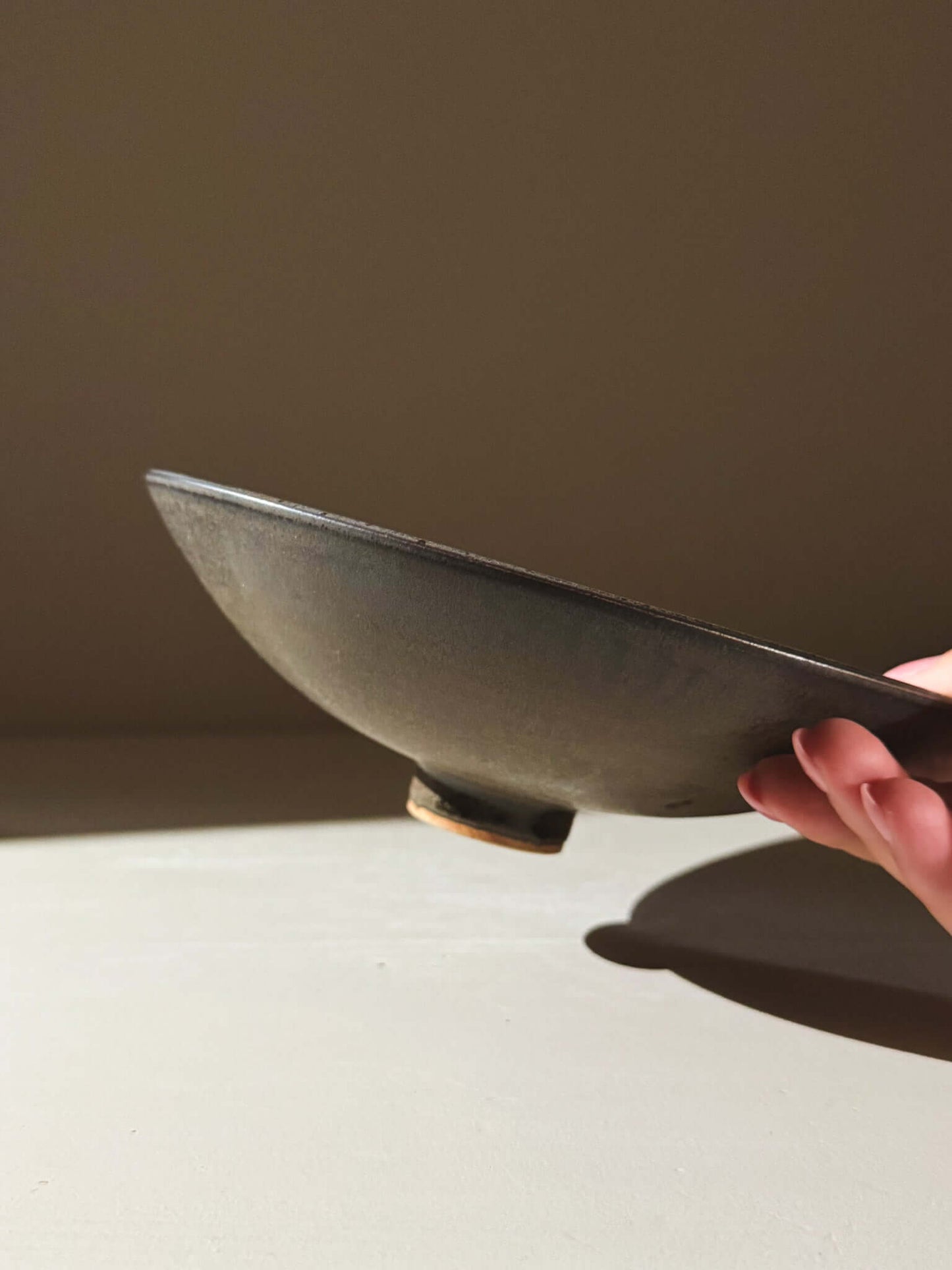 Side view of the Footed Serving Bowl – Black Truffle #01, highlighting the matte black glaze and speckled stoneware clay.