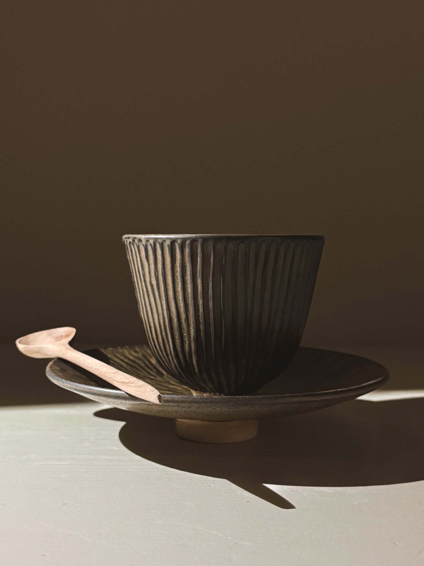 Carved Footed Plate – Black Truffle with intricate sunburst pattern in dark glaze, showcasing texture and depth.