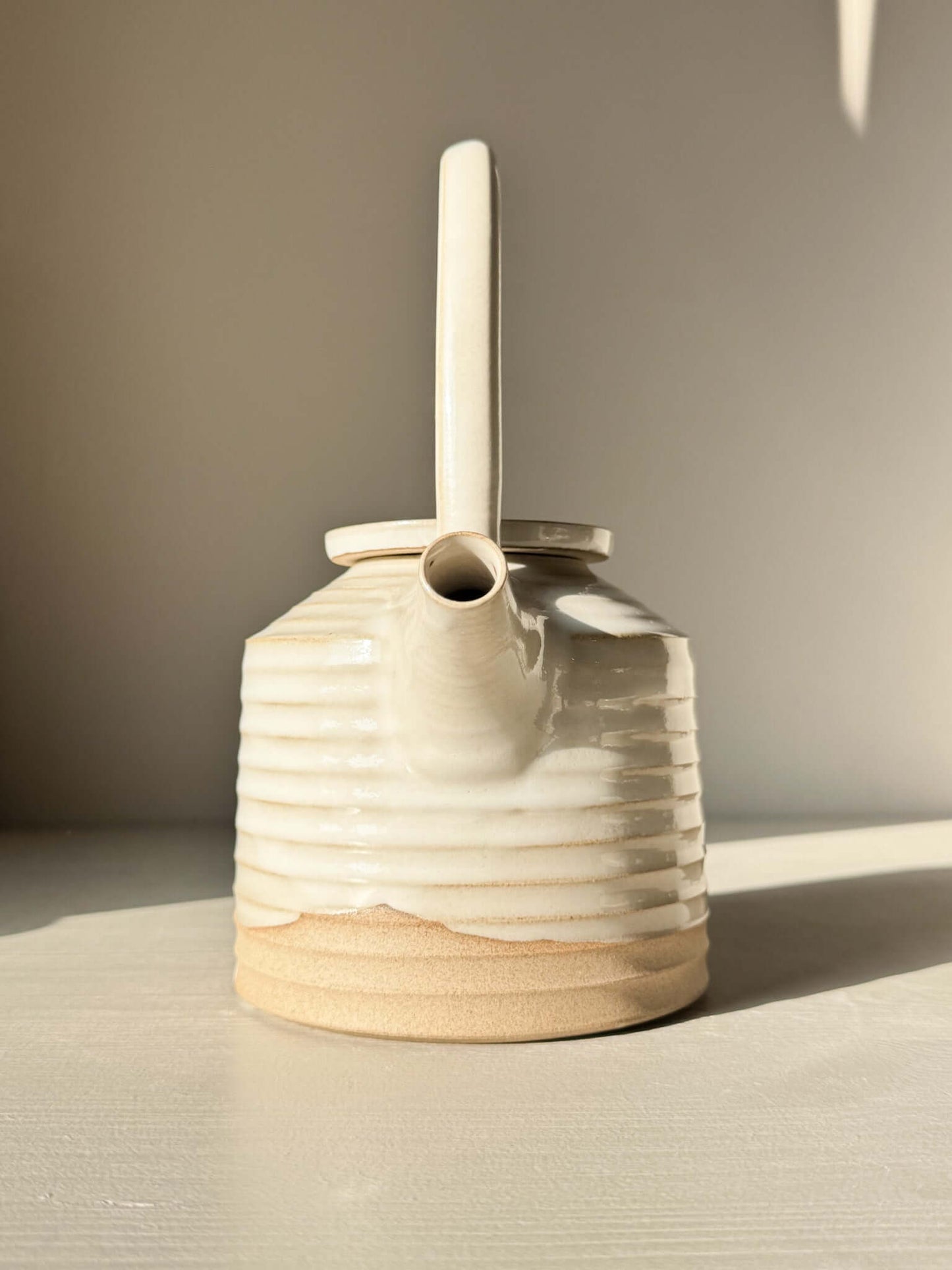 Teapot - Yuki Series #01 handmade ceramic with tall looped handle, soft curves, and white glaze over raw clay.