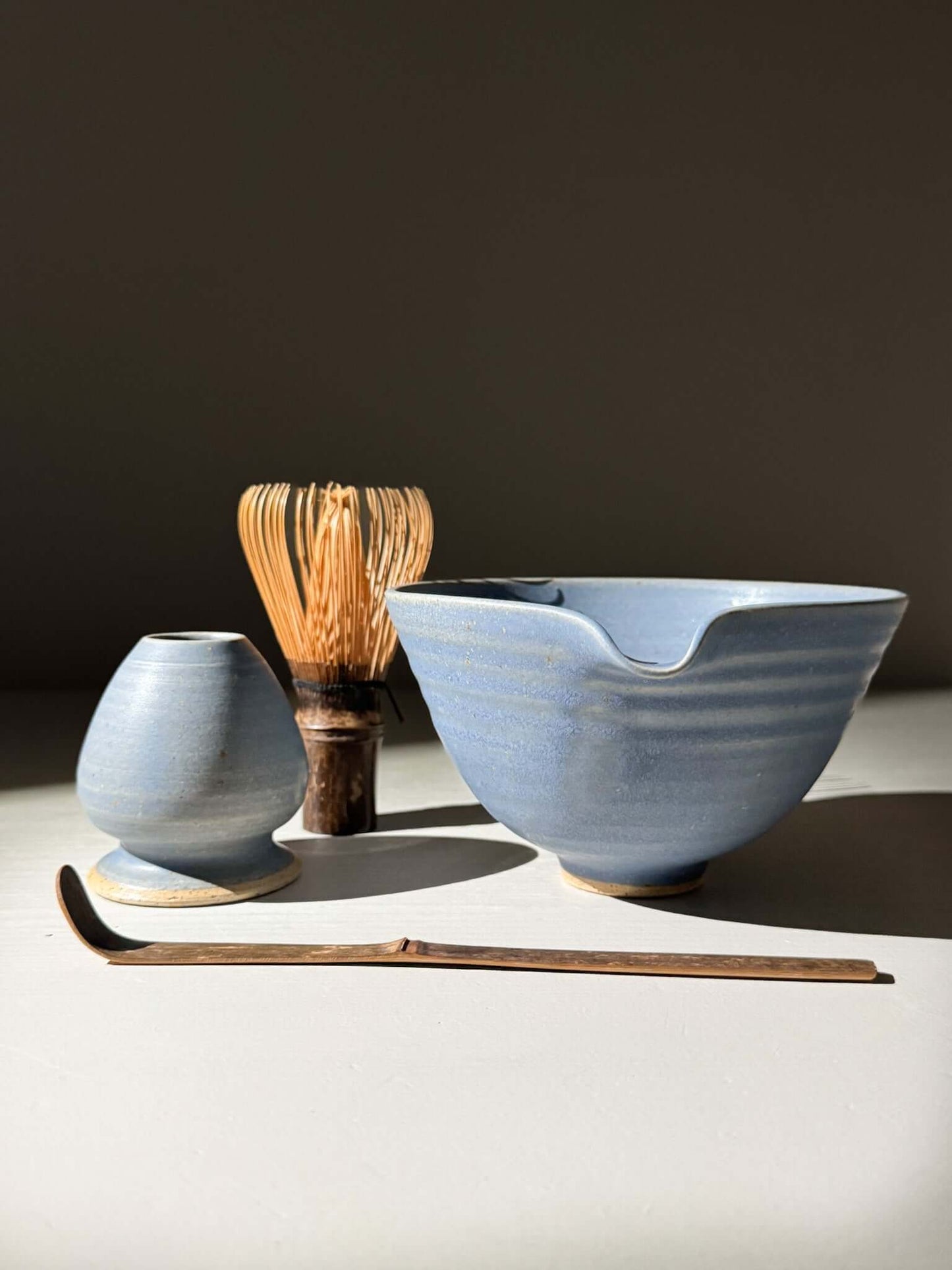 Matcha Bowl & Whisk Holder Set - Blue #01 with blue glaze, pouring spout, and bamboo whisk holder under soft lighting.