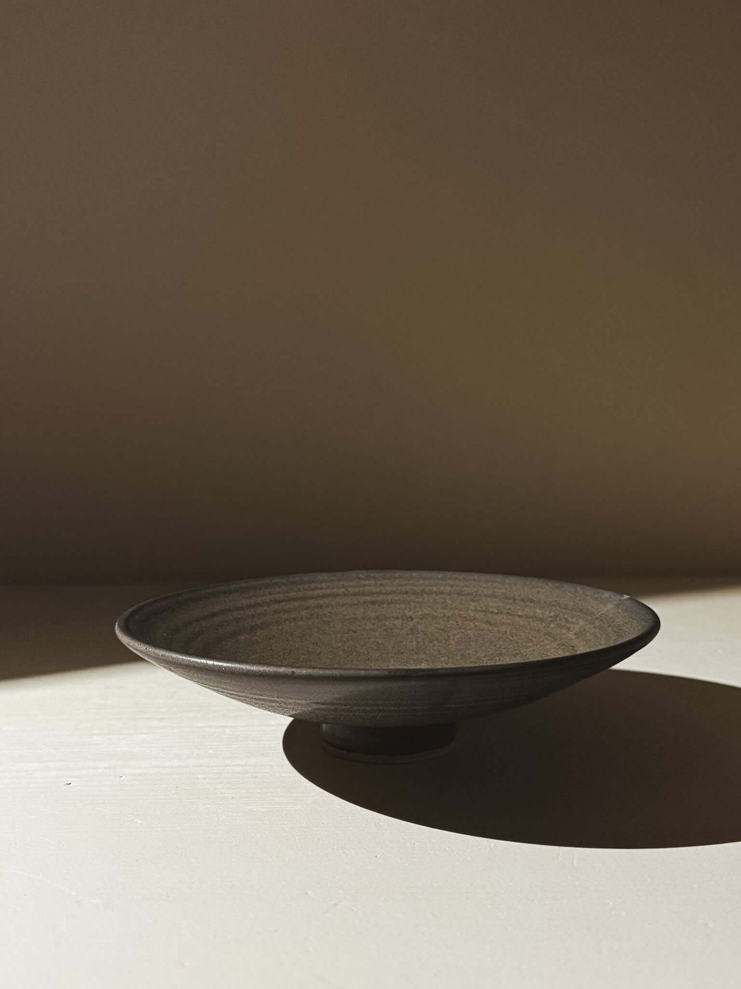 Footed Serving Bowl – Black Truffle #02 in matte black glaze on speckled stoneware clay showing depth and character.