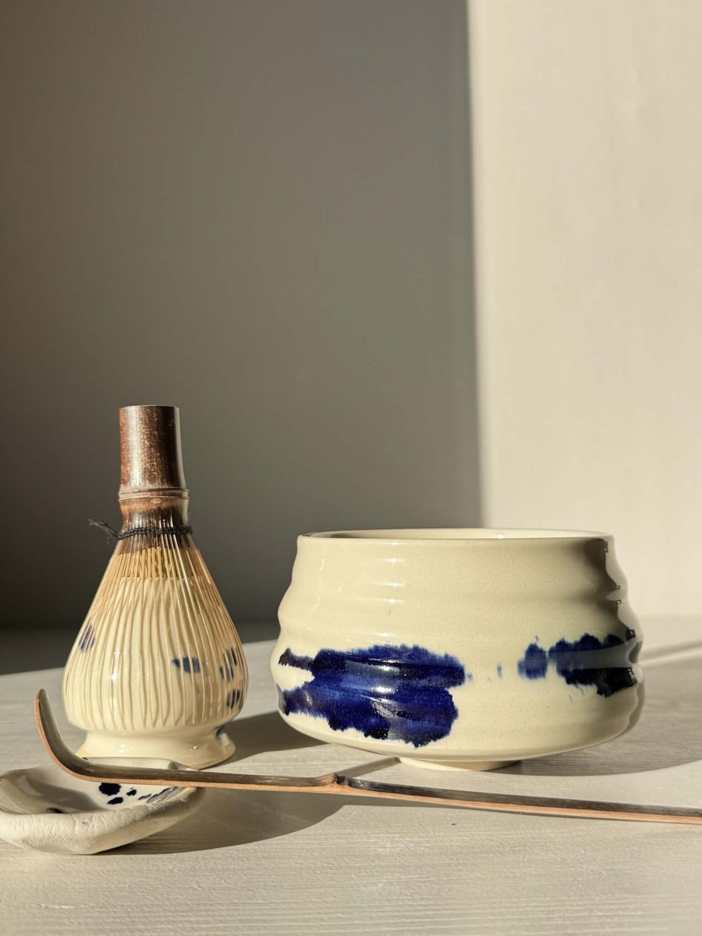 Matcha Bowl – Gosu Series #02 with cobalt glaze and rounded design beside traditional whisk