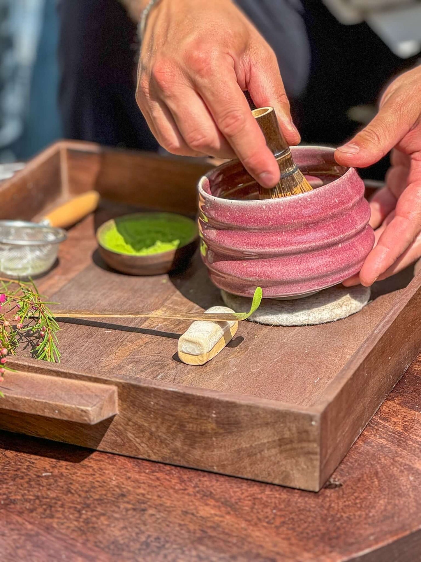 Person preparing tea with pink Matcha Bowl from Ume Series, inspired by Japanese blossom, featuring flowing ridges and wide foot.