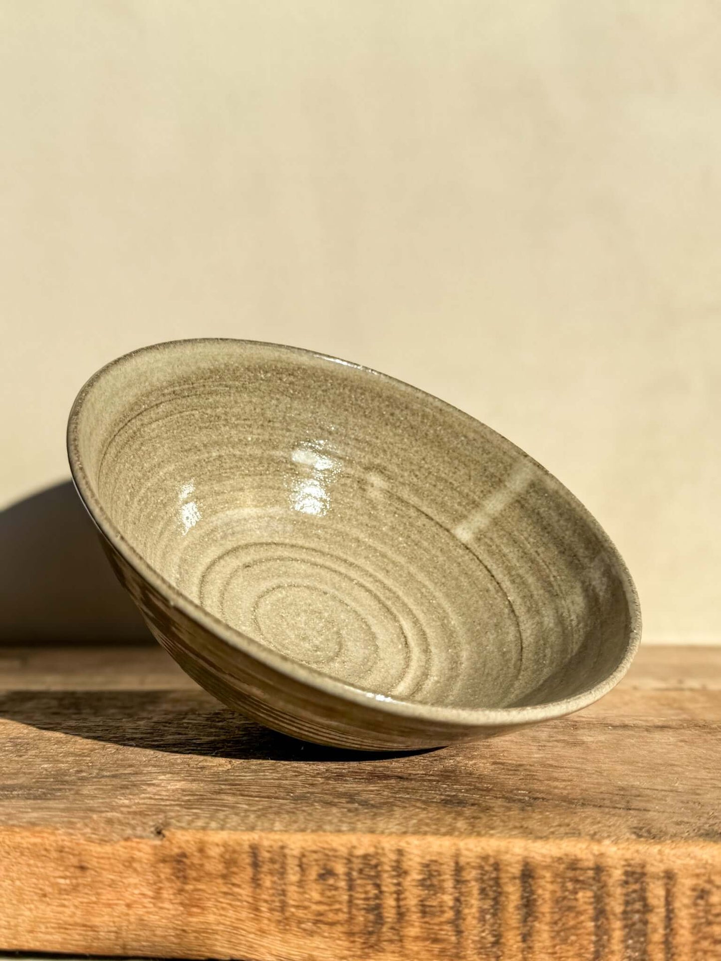 Handcrafted Yuki Series dark clay bowl with white glaze and wheel-thrown details, showcasing its wide, open design on a wooden surface.
