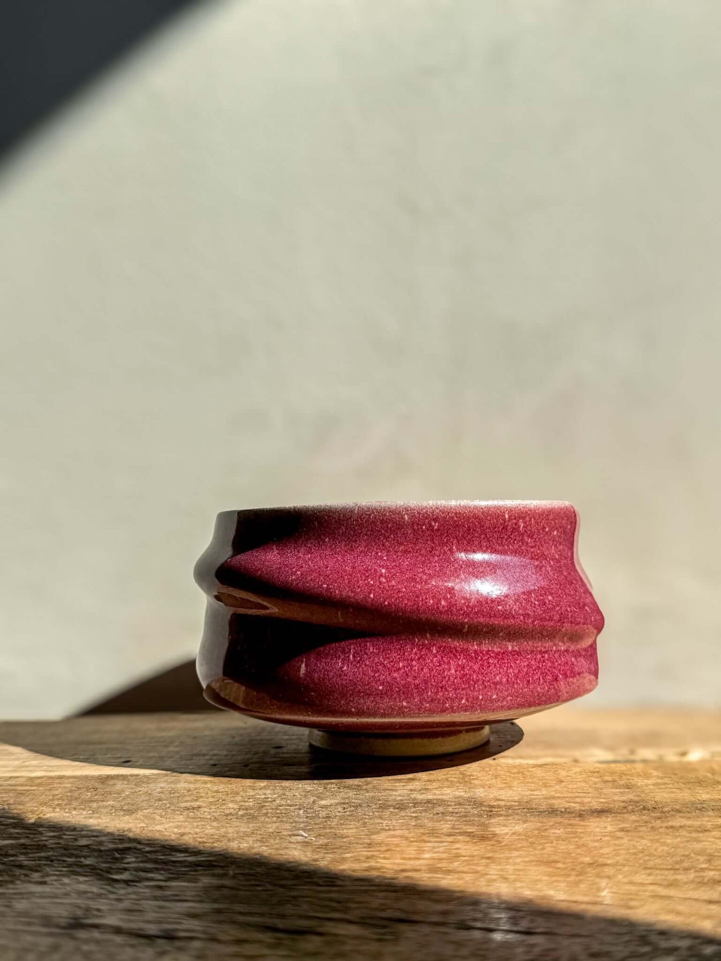 Ume Series #05 Matcha Bowl with sculptural ridges, inspired by Japanese ume blossom, in vibrant pink color, on a wooden surface.
