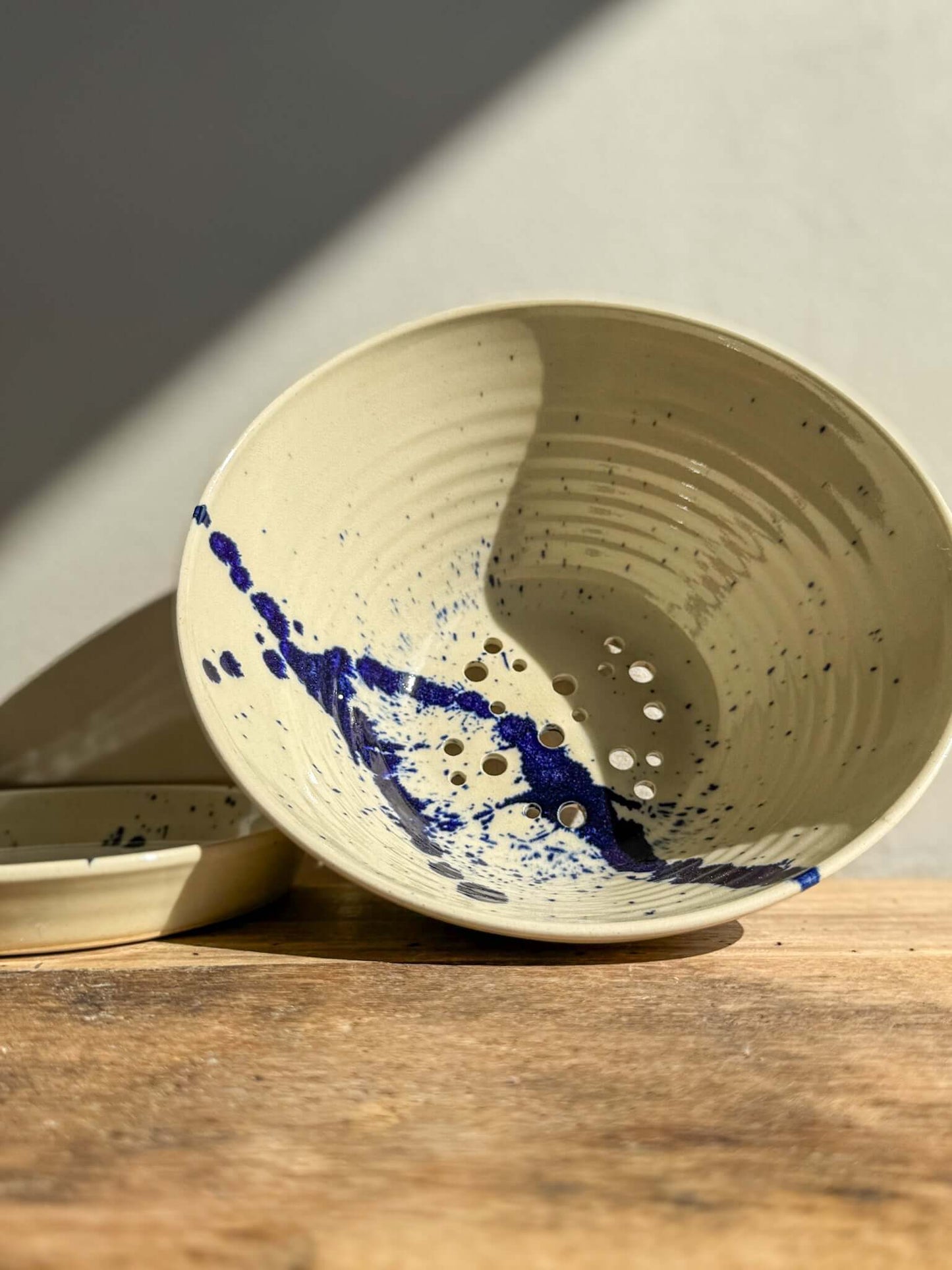 Gosu Series sculptural berry bowl with cobalt blue splashes, designed for rinsing fruit, featuring a clear glaze and matching drip plate.