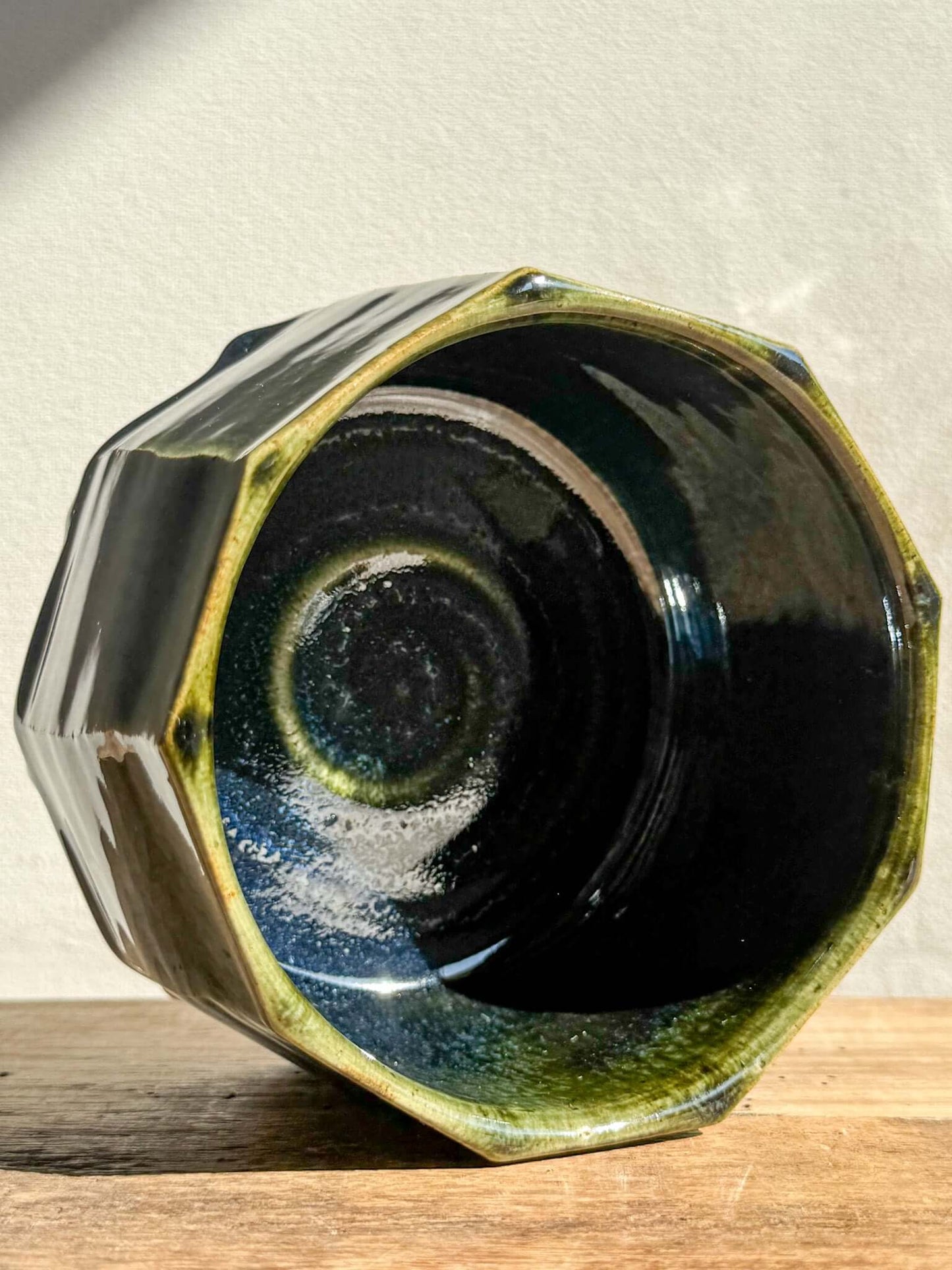 Faceted matcha bowl from Hinoki Series with deep green glaze and hand-carved facets, highlighting rich textures and moody pools.