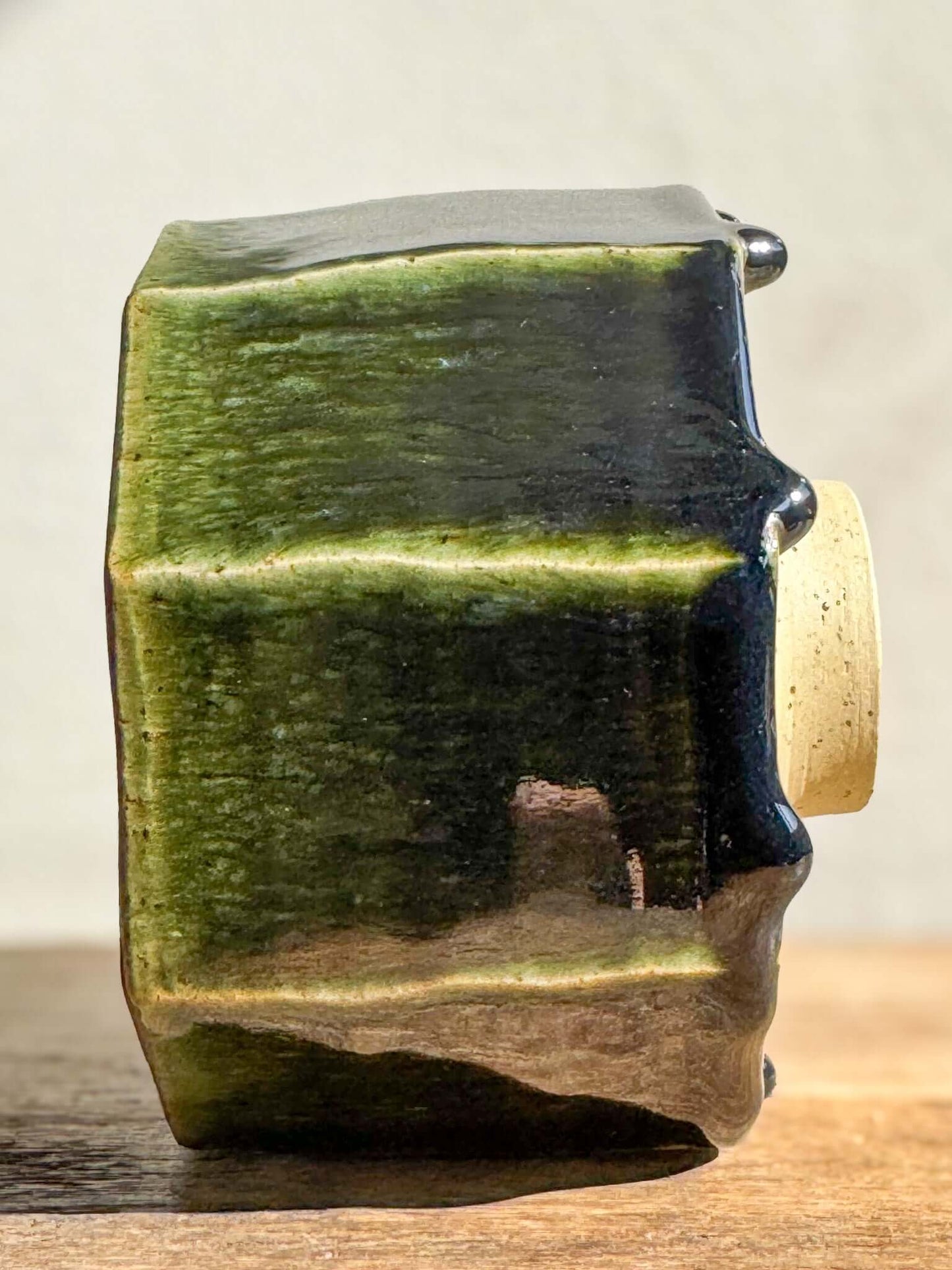 Faceted matcha bowl with deep green glaze from Hinoki Series, showing handmade carved lines and light-reflecting facets.