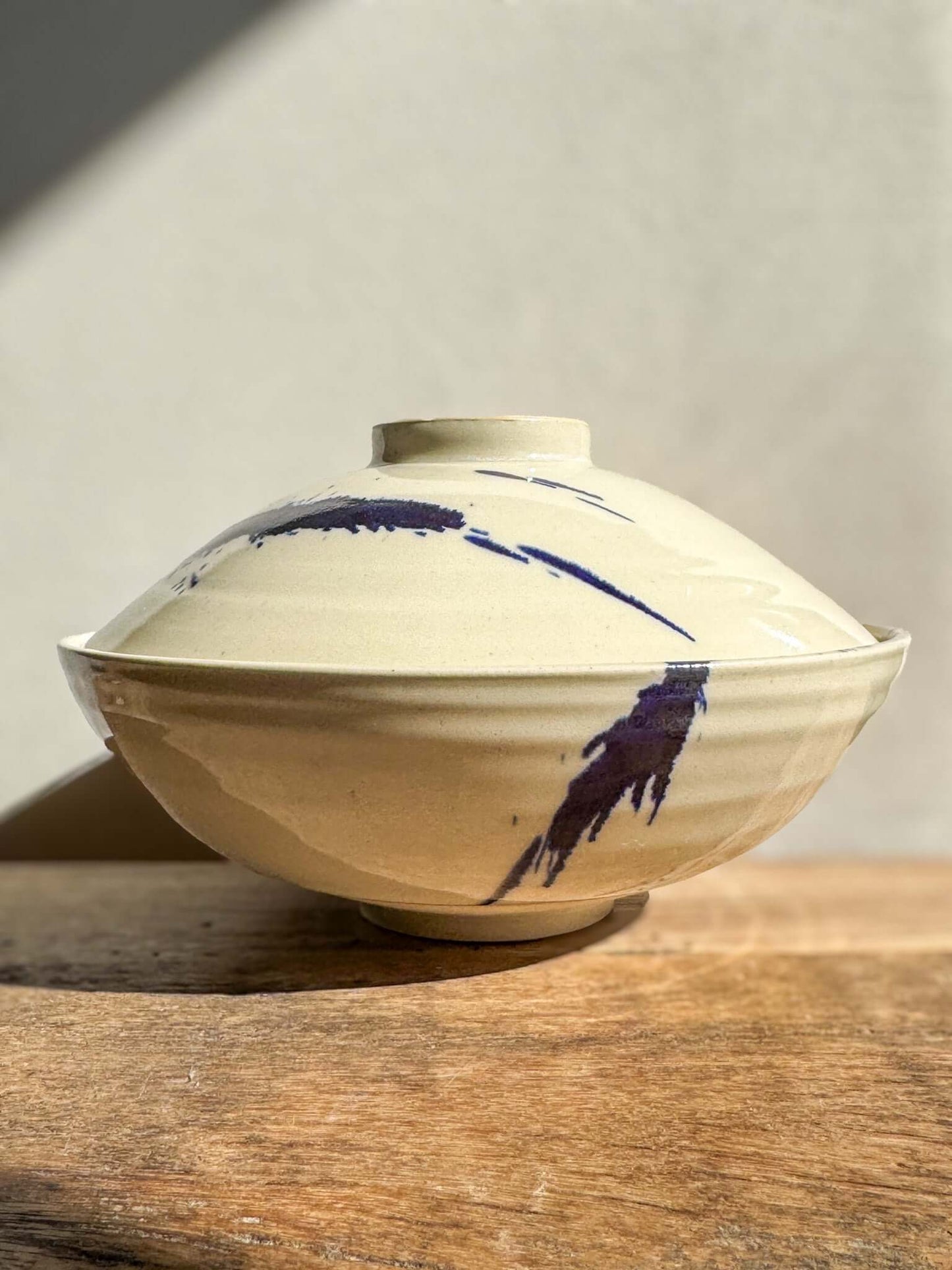 Lidded serving bowl from Gosu Series with cobalt splashes, wheel-thrown design, adding unique beauty and artistic flair to any table.