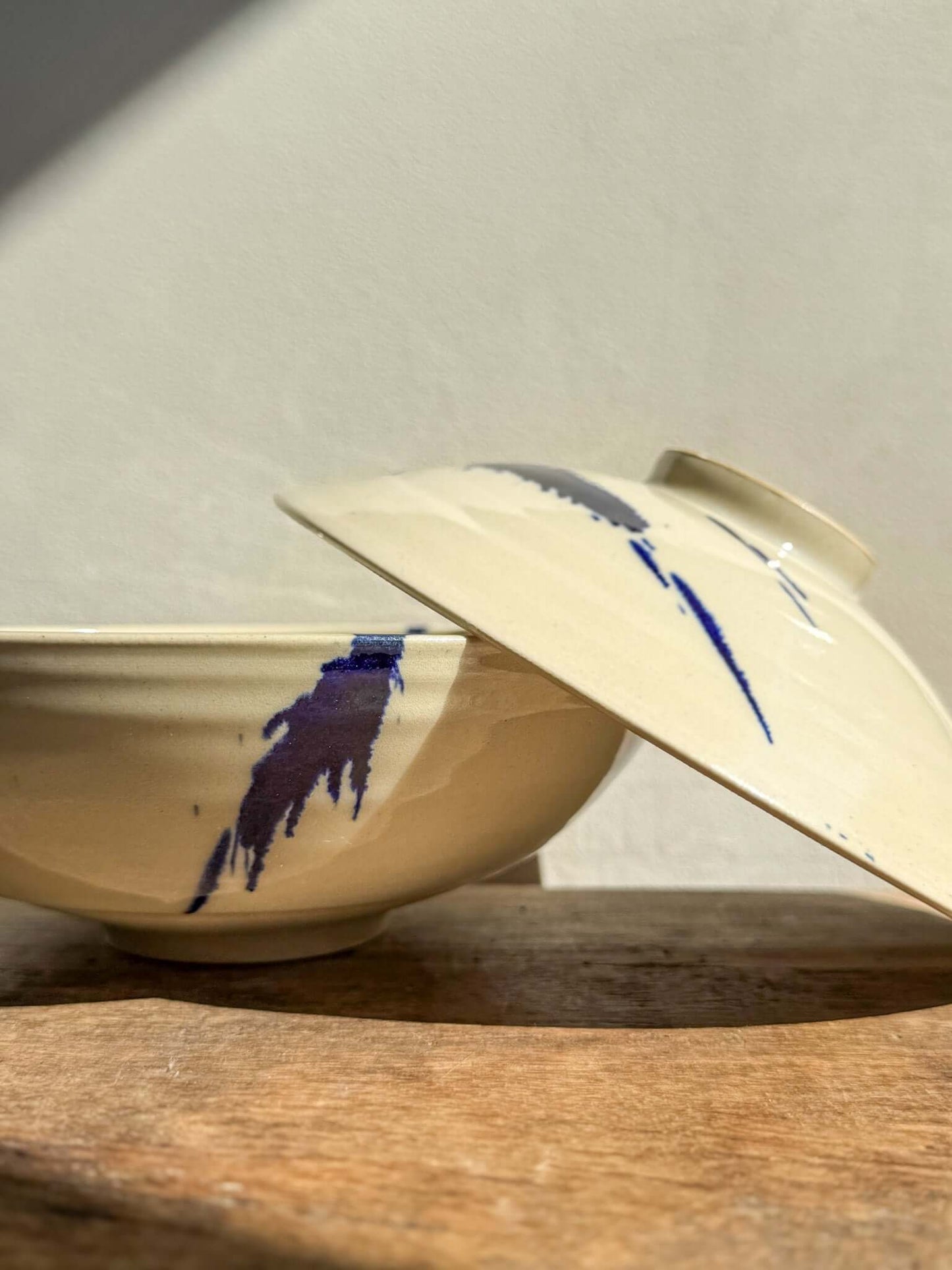 Lidded Serving Bowl with cobalt splashes, Gosu Series, featuring bold, unique designs on a rustic wooden surface.