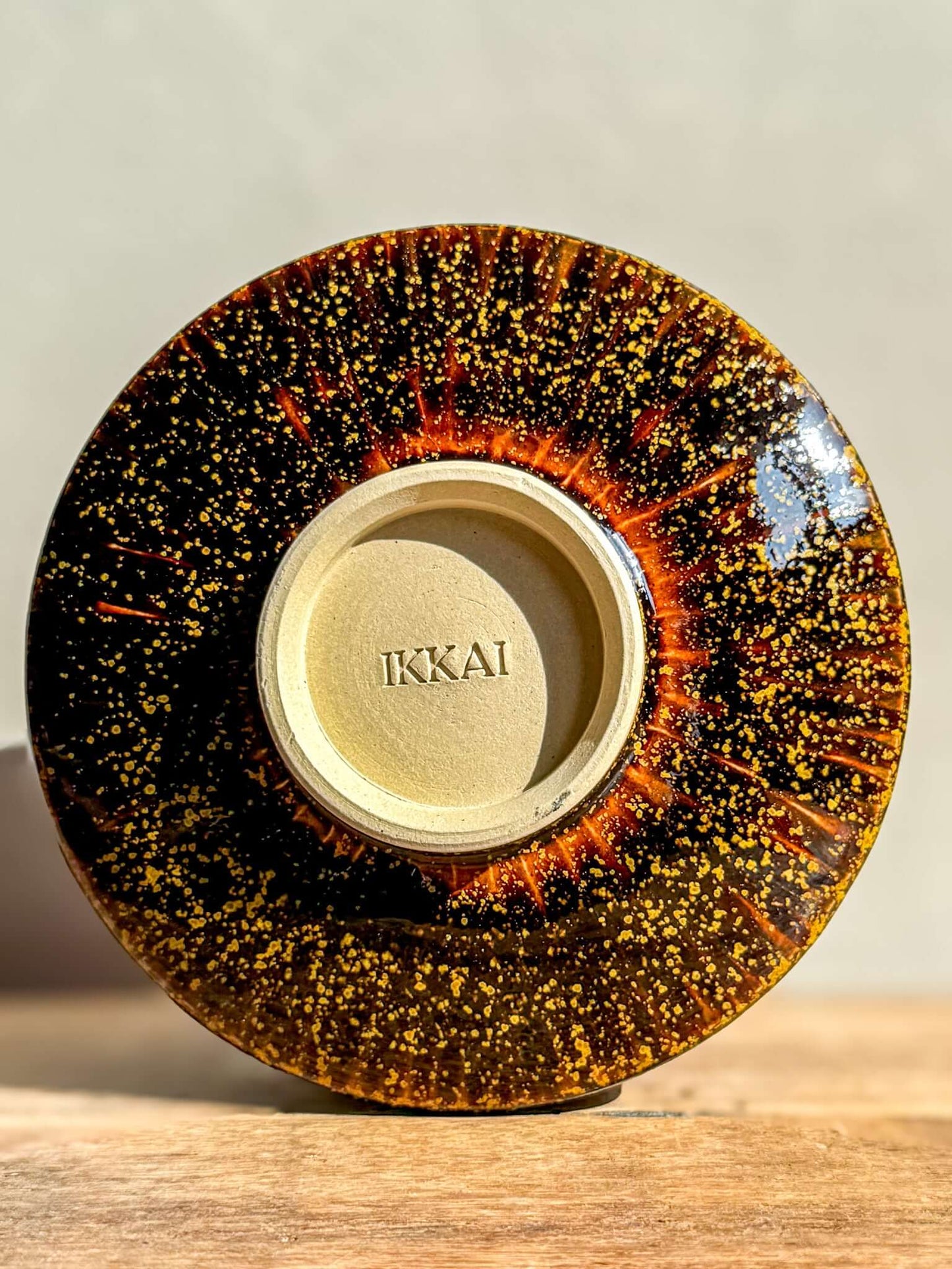 Base view of Kinsei Matcha Bowl #01 with spiral gold and orange design, handcrafted with a glossy brown finish, by Ikkai.