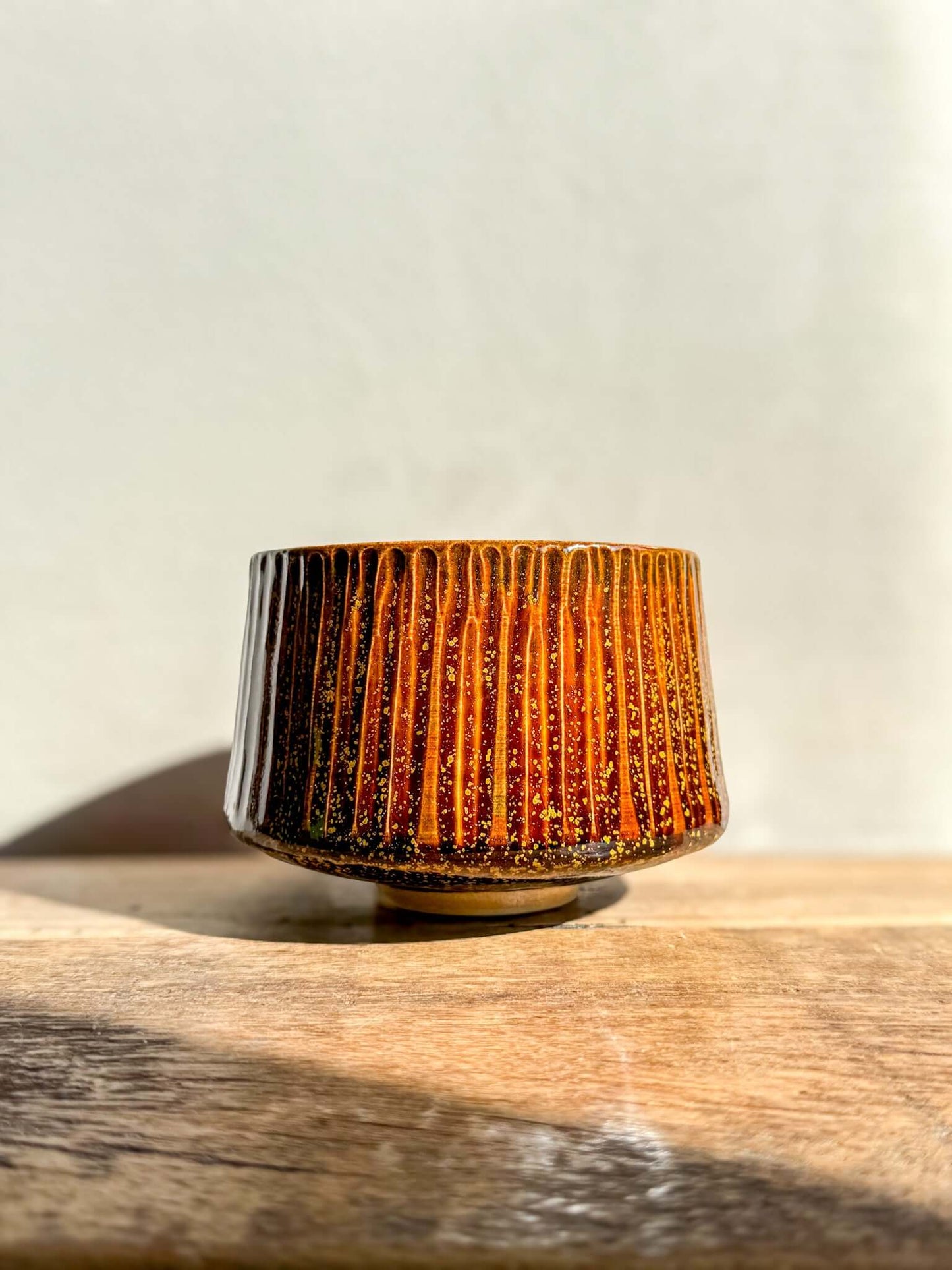 Kinsei Matcha Bowl #01 with glossy brown glaze and gold spiral inside, resembling a galaxy. Rounded shape, vertical texture.