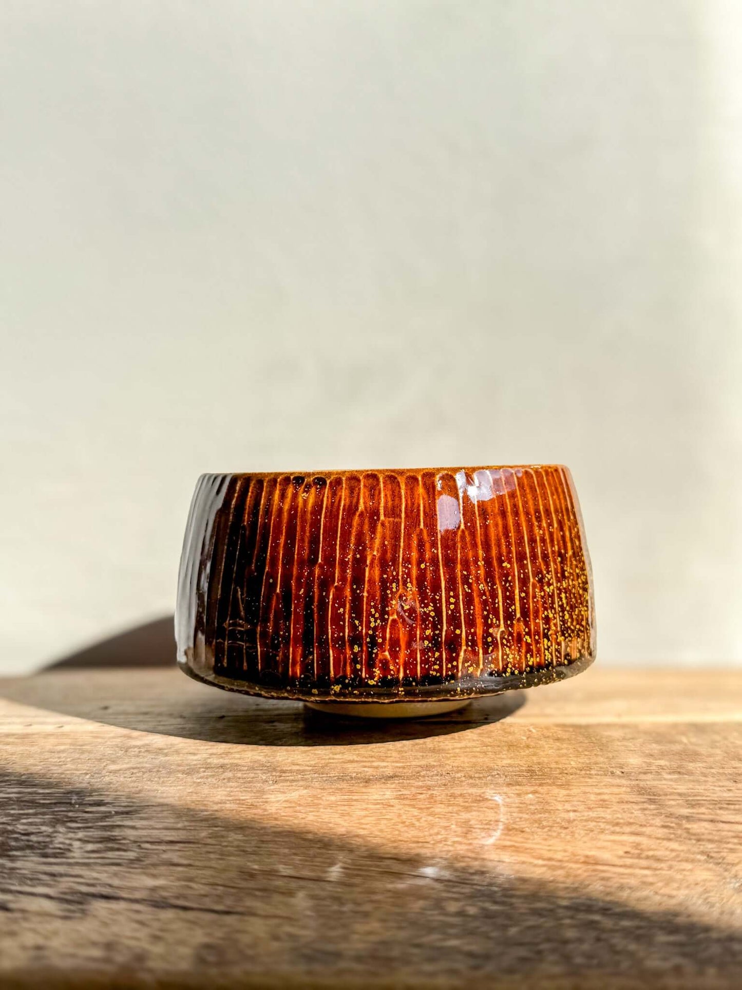 Kinsei Matcha Bowl #03 with glossy brown glaze and golden spiral design, inspired by a galaxy, on wooden surface.