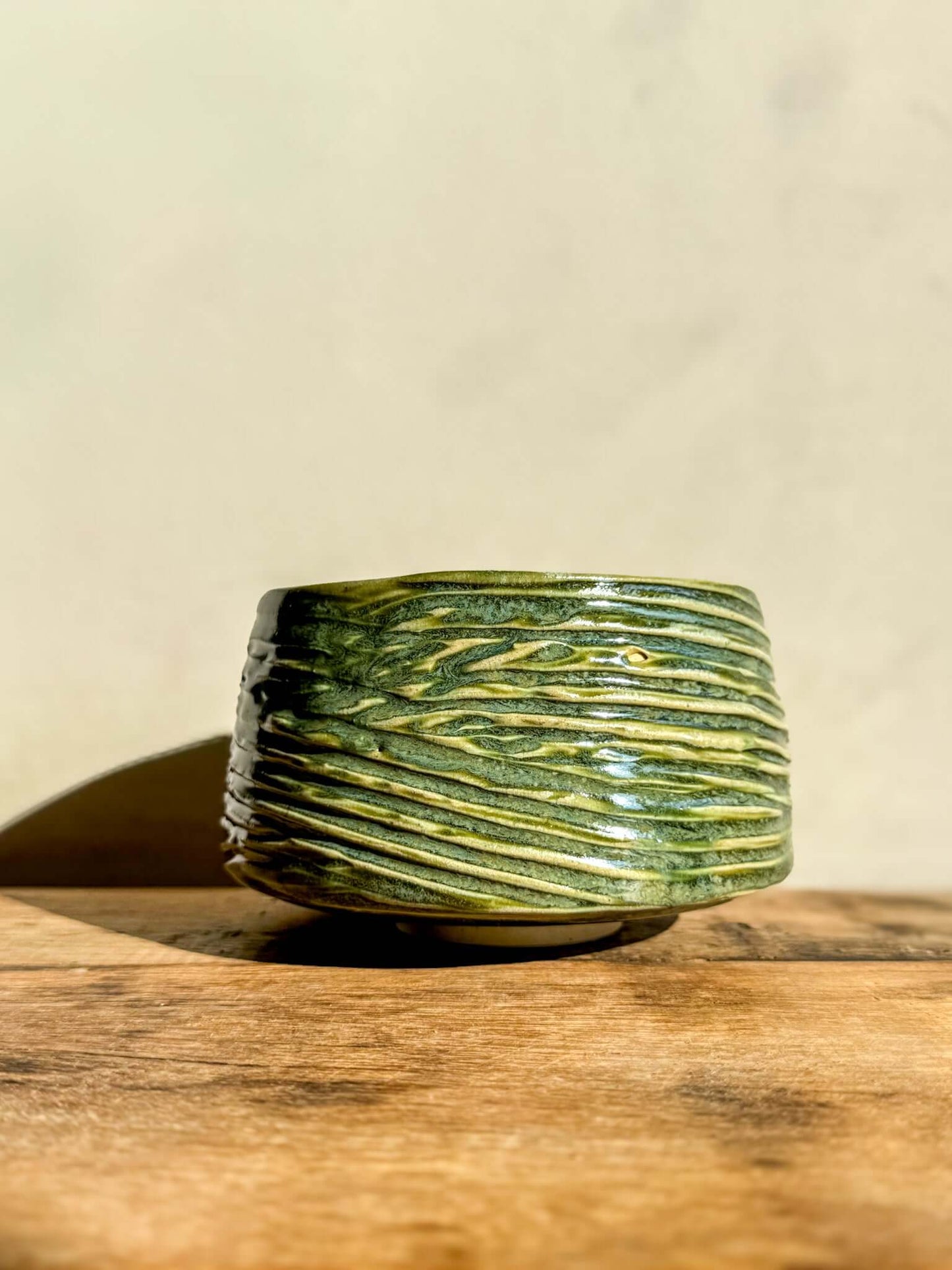 Handcrafted Wasabi Green matcha bowl with textured, carved lines and glossy finish, evoking movement and quiet energy.
